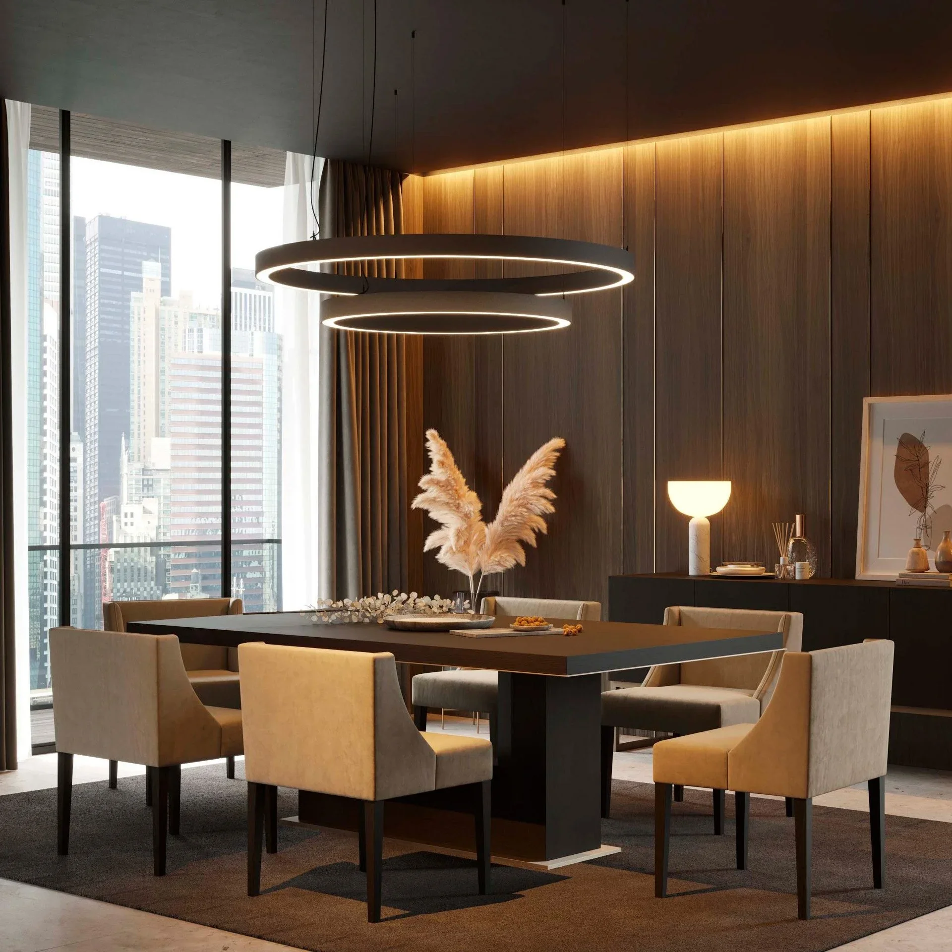 Modern dining room with six beige upholstered chairs around a dark rectangular table, decorated with a vase of pampas grass. Large windows reveal a city skyline. Black pendant lights hang above the table. A black sideboard with decorative objects, a 