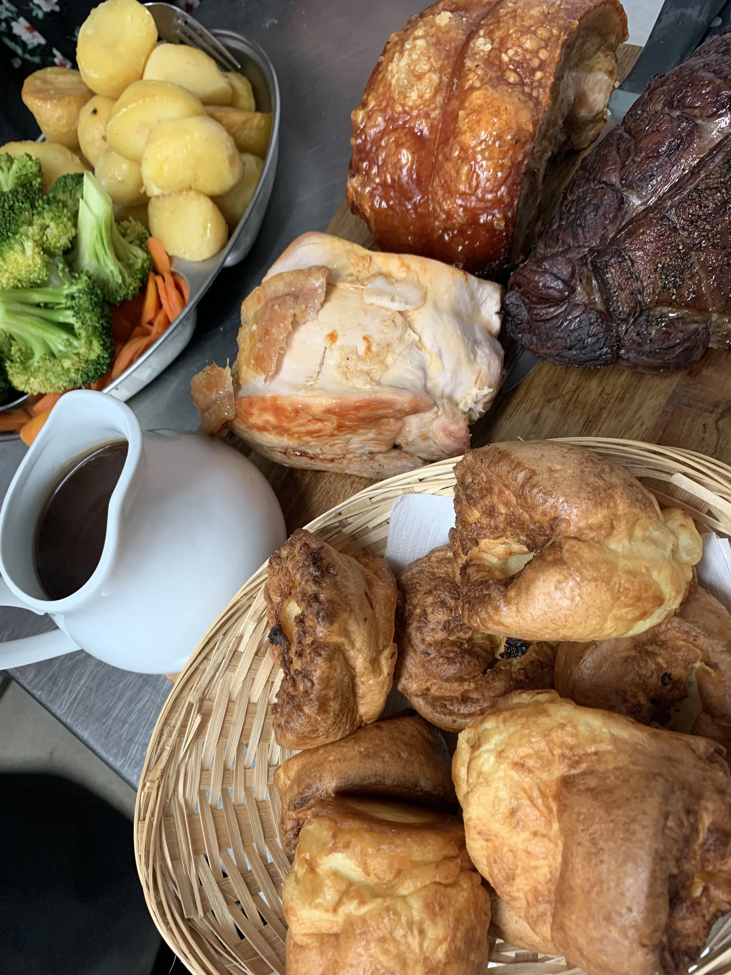 A traditional Sunday roast meal with roast beef, roast chicken, Yorkshire pudding, roast potatoes, mixed vegetables, and gravy.