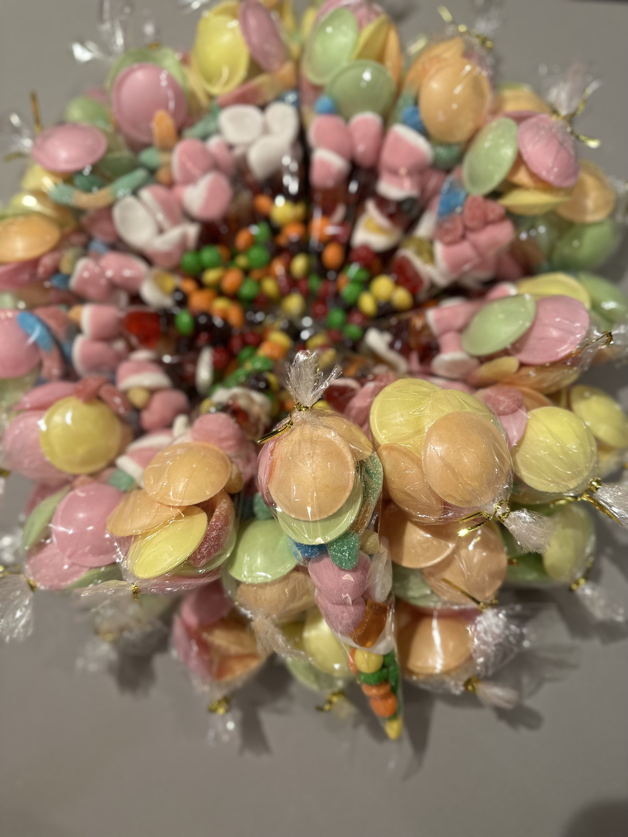 Colorful assorted candies including gumdrops, jelly beans, and wrapped candies arranged in a cupcake shape.
