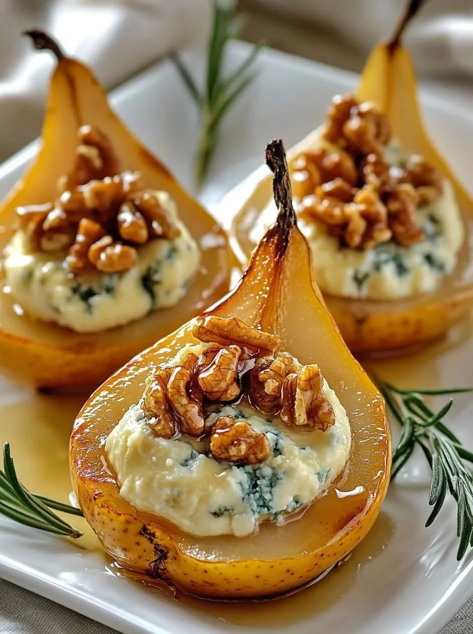 Pear halves filled with blue cheese, topped with walnuts, and garnished with rosemary on a white platter.