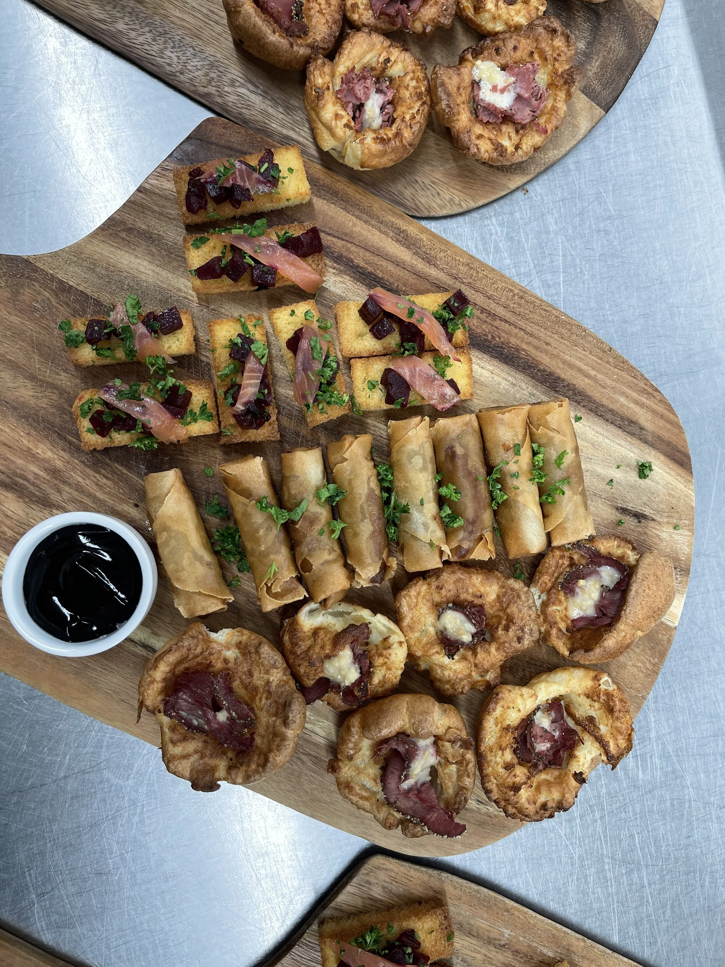 Assorted appetizers on wooden serving boards, including mini pizzas, fried cheese bites, spring rolls, and breaded stuffed mushrooms.