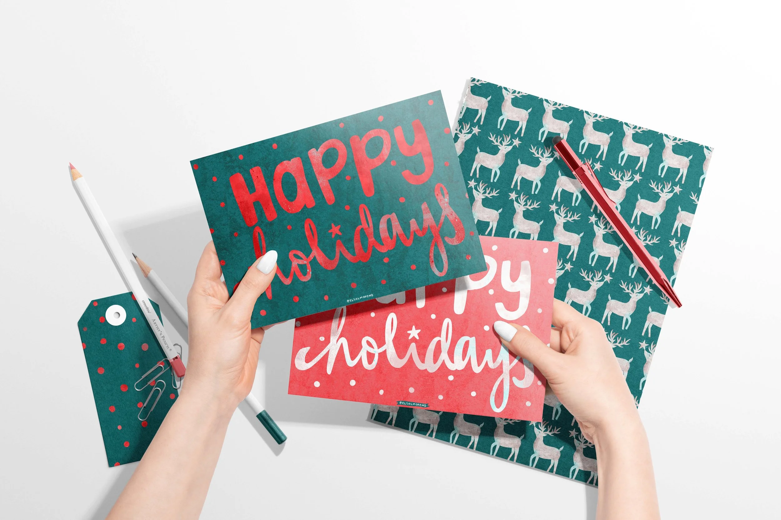 Christmas stationery set featuring two cards with a handwritten "Happy Holidays" message, one with red letters over a green background, and one with white letters over a red background. There is also a notebook featuring a cover of a repeating patter