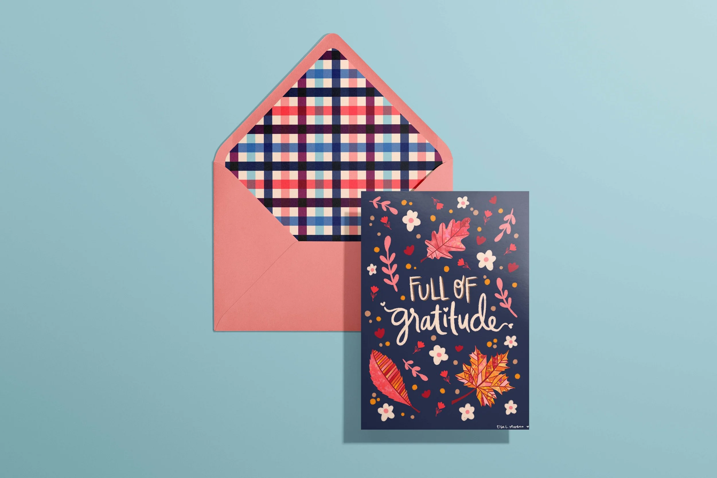 A card and envelope featuring leaves, branches and flowers in autumnal colors and the hand lettered message "Full of Gratitude". The envelope features a coordinating gingham pattern inside.