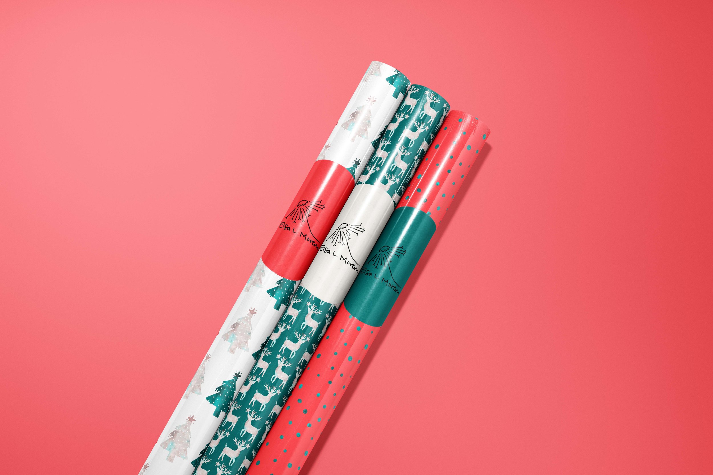 Three rolls of gift wrapping paper, one featuring Christmas trees over a white background, another one with white reindeer over a dark green background and a silver dotted one with a red background