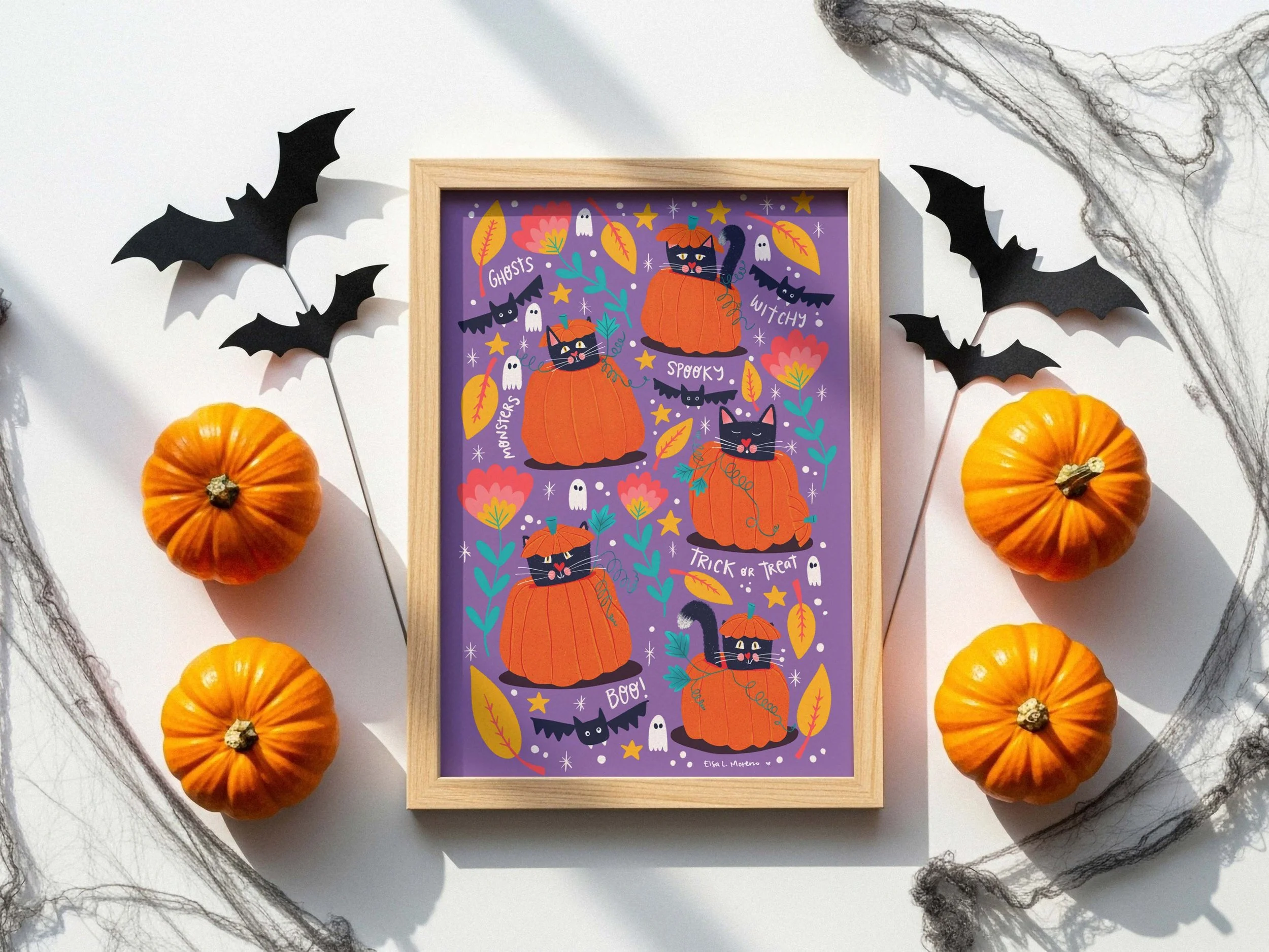 A wooden frame with an illustration of five stylized black cats inside carved pumpkins, surrounded by yellow leaves and red flowers, stars, ghosts and bats, all over a purple background. The words Ghosts, Witches, Spooky, Boo! and Trick or Treat are 