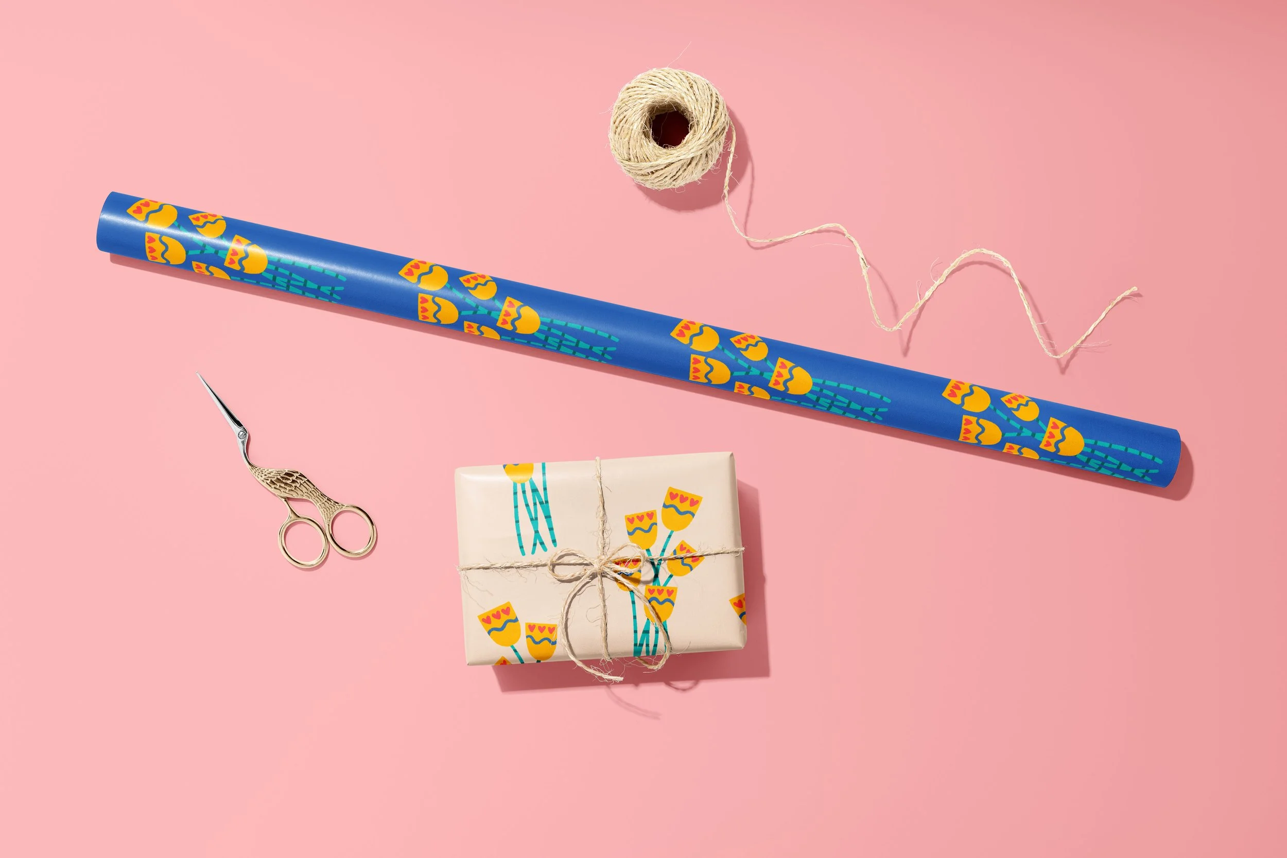 A gift wrapped with a tulip on an ecru background motif wrapping paper, a roll of the same tulip wrapping paper with a blue background