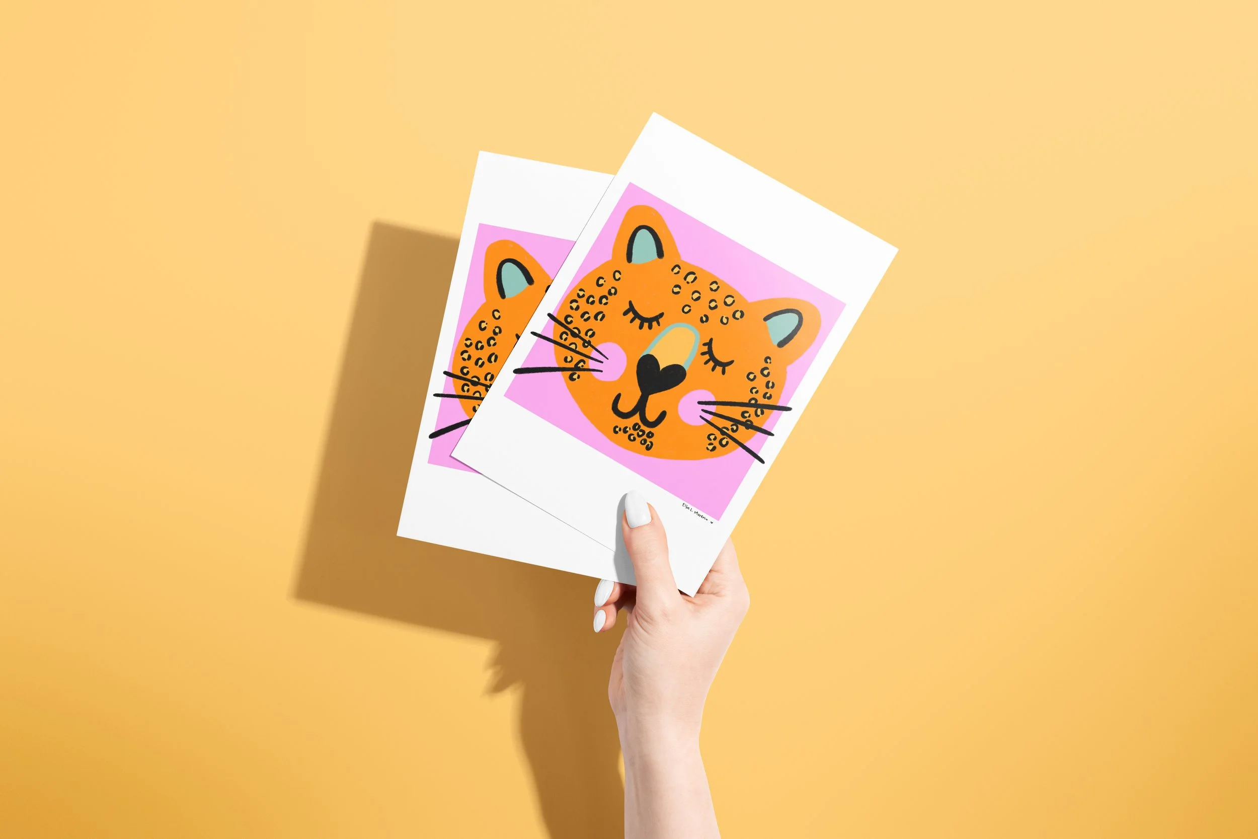 Image shows a hand holding two cards depicting a leopard on a pink background
