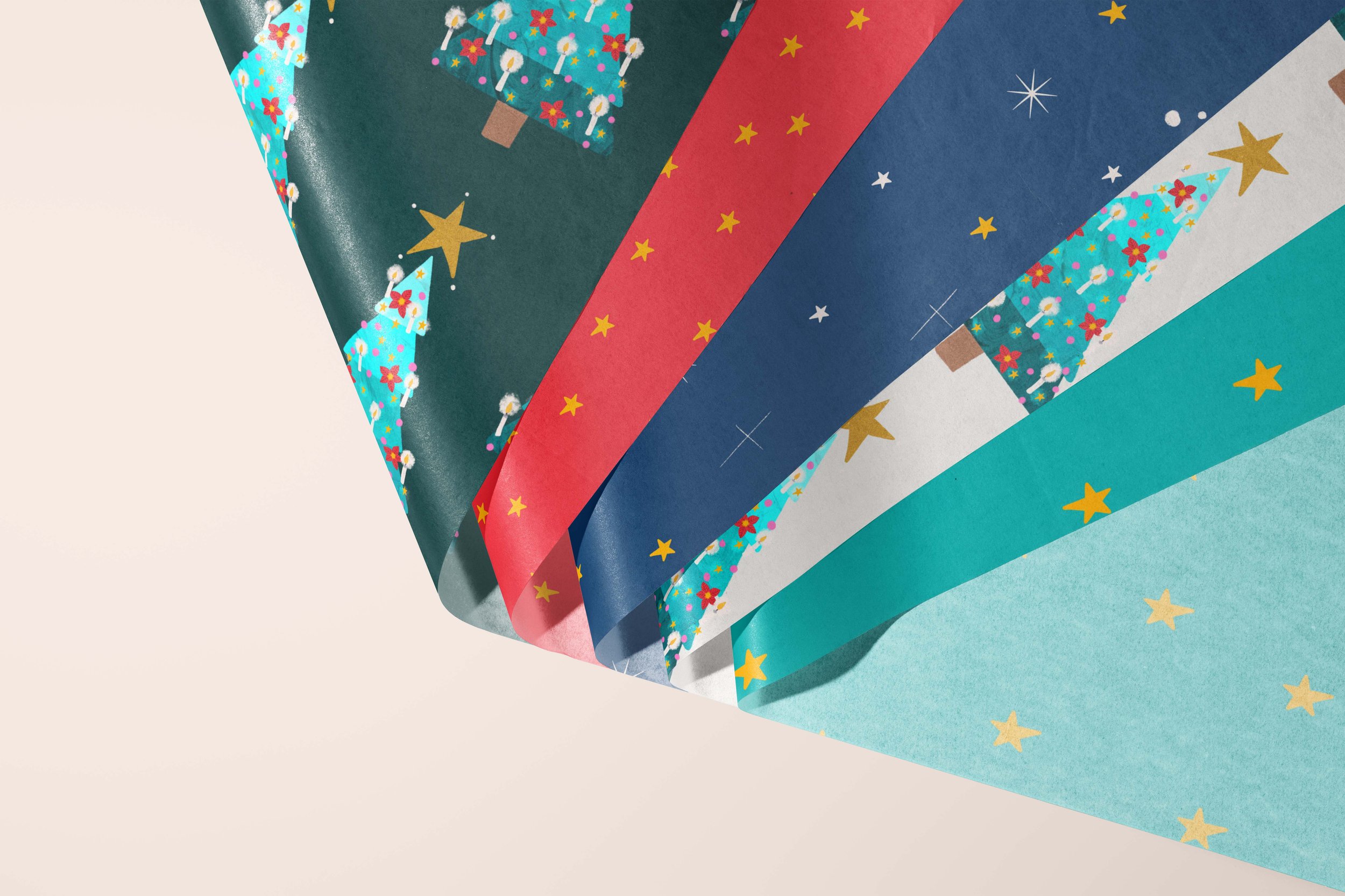 Five tissue papers folded in a fan-like shape, each featuring a different Christmas pattern: one of Christmas trees over a dark green background, one of yellow stars over a red background, one of yellow and white stars over a dark blue background, on
