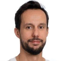 Portrait of a man with short dark hair and a beard on a white background.