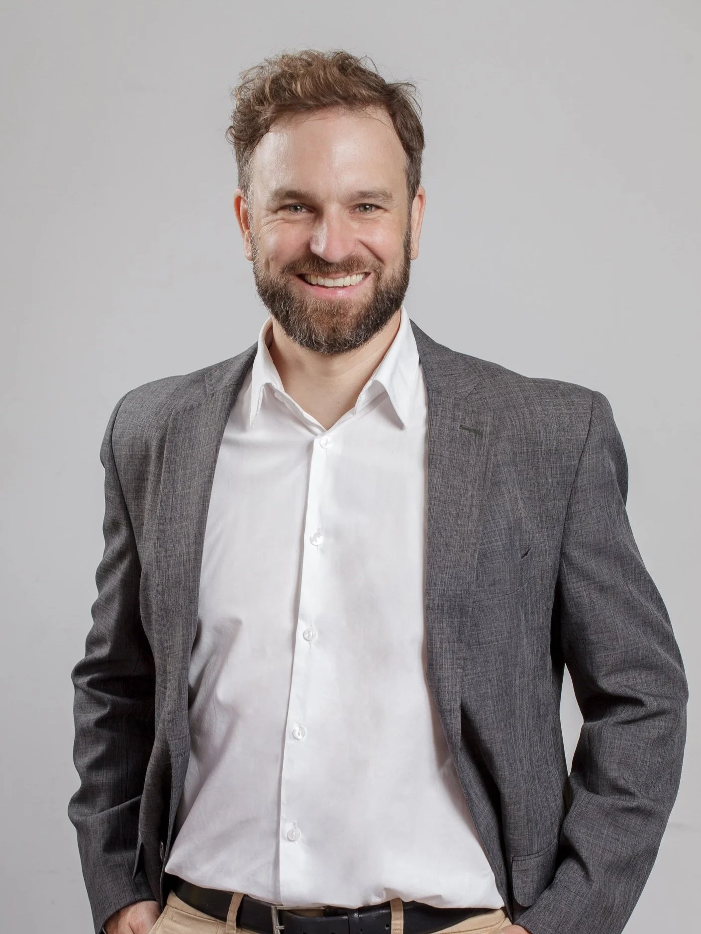 Man smiling in gray suit jacket and white shirt