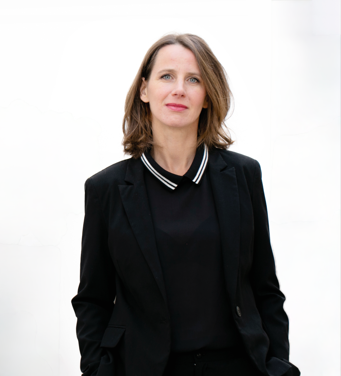 A portrait of a woman with brown hair and blue eyes, wearing a black jacket, smiling at the camera.