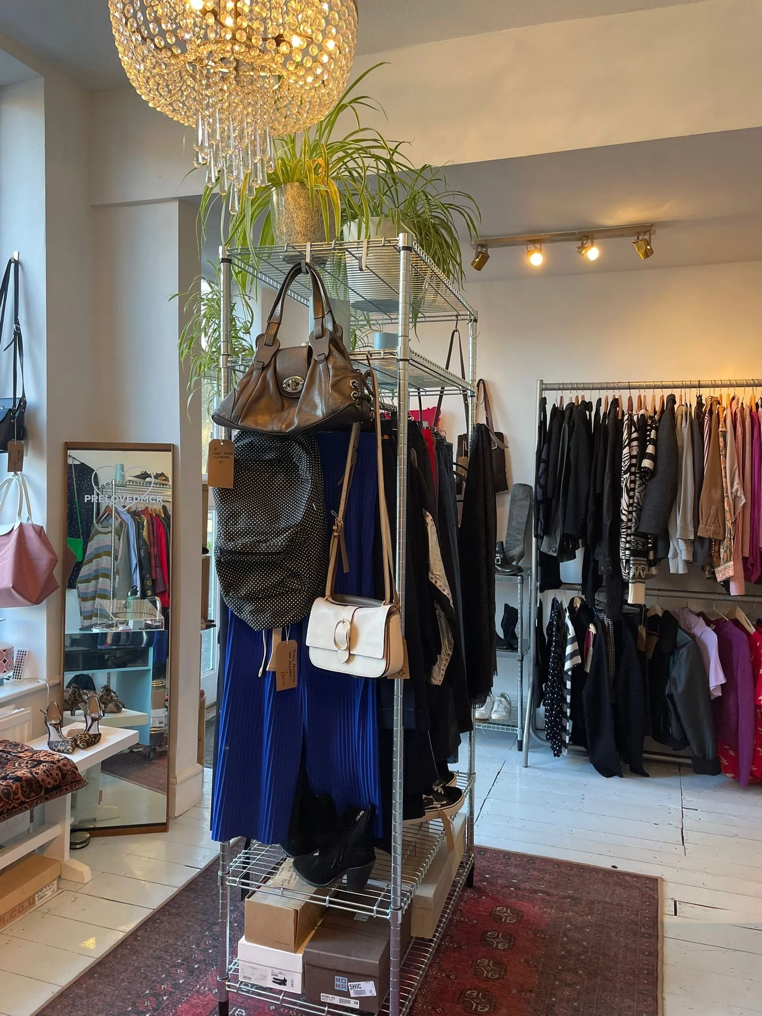preloved clothes on a rail with chandelier light and plants