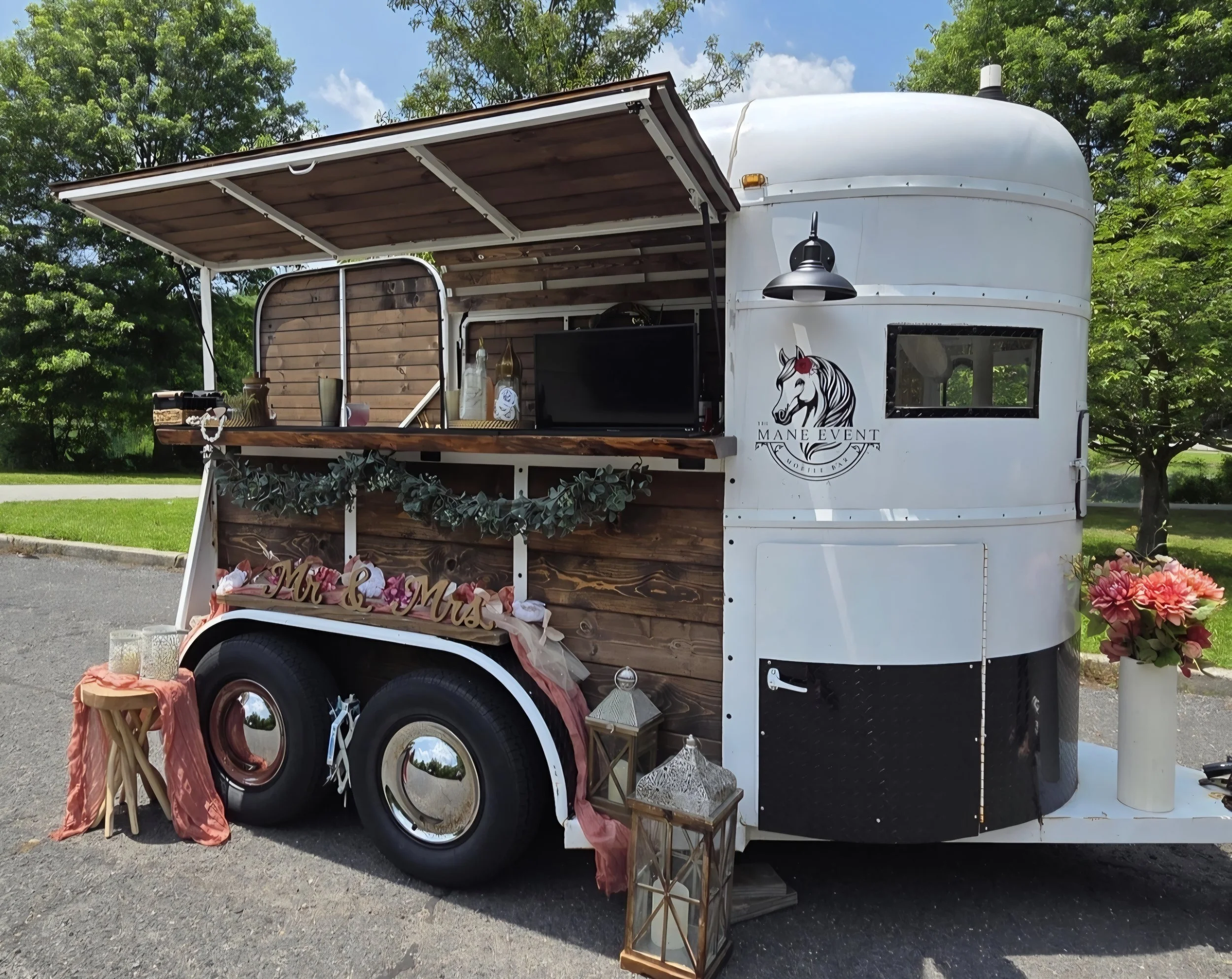 The Show Stopper, our vintage style horse trailer decorated and set up ready to serve n outdoor event, with floral arrangements, lanterns.