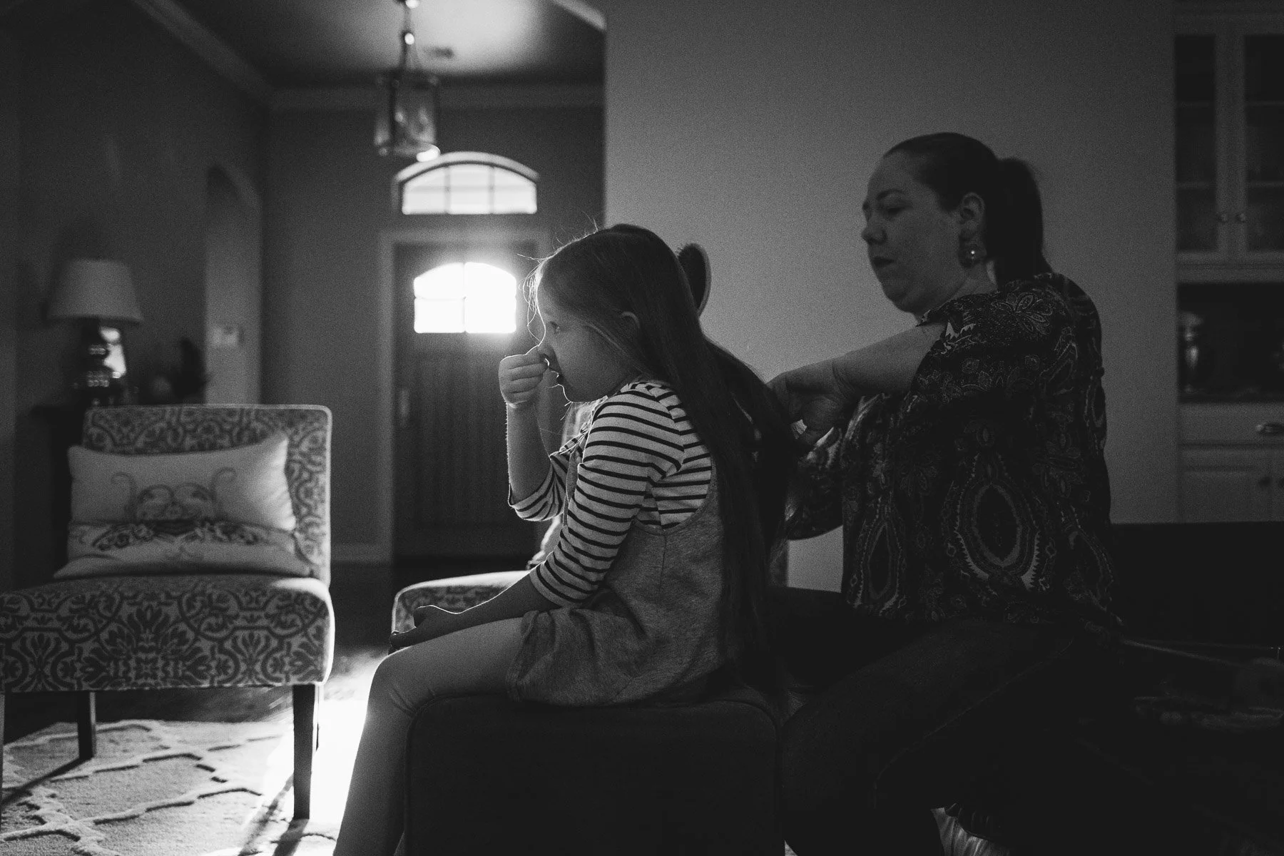 Girl picking her nose while getting her hair brushed