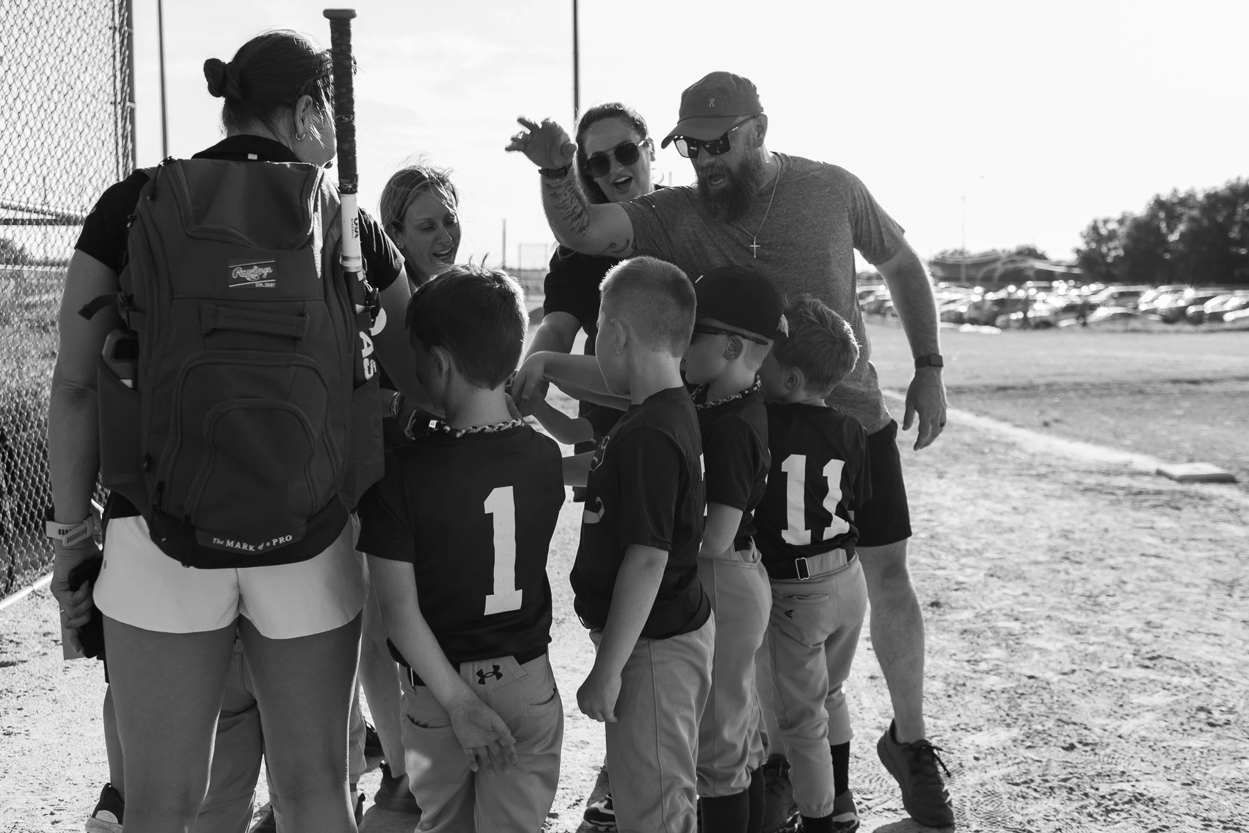 A huddle of Little League baseball players and their coaches