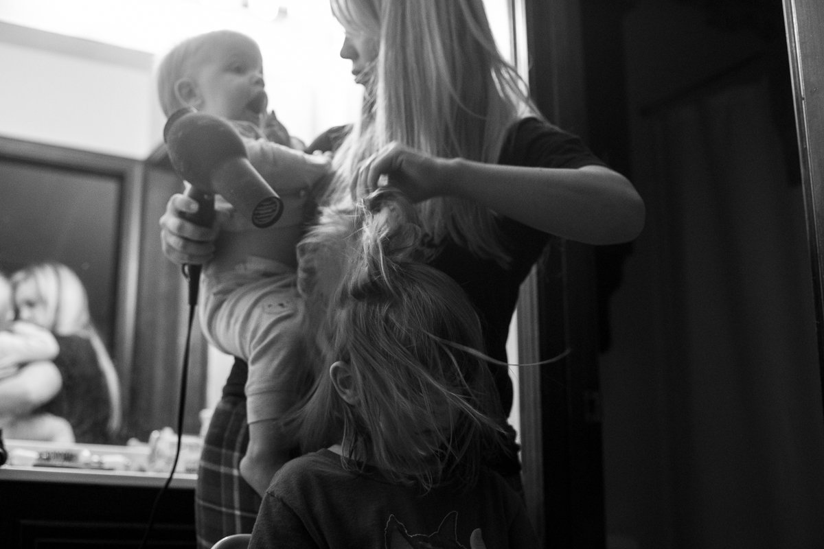 Mom holding baby and blowdrying girl's hair