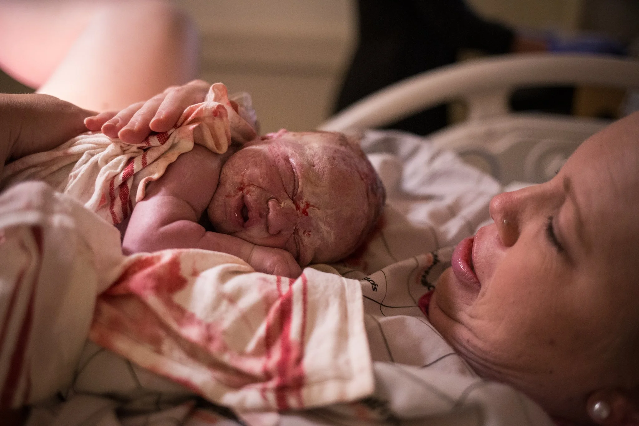 A woman lying in a hospital bed holding her newborn baby after delivery.