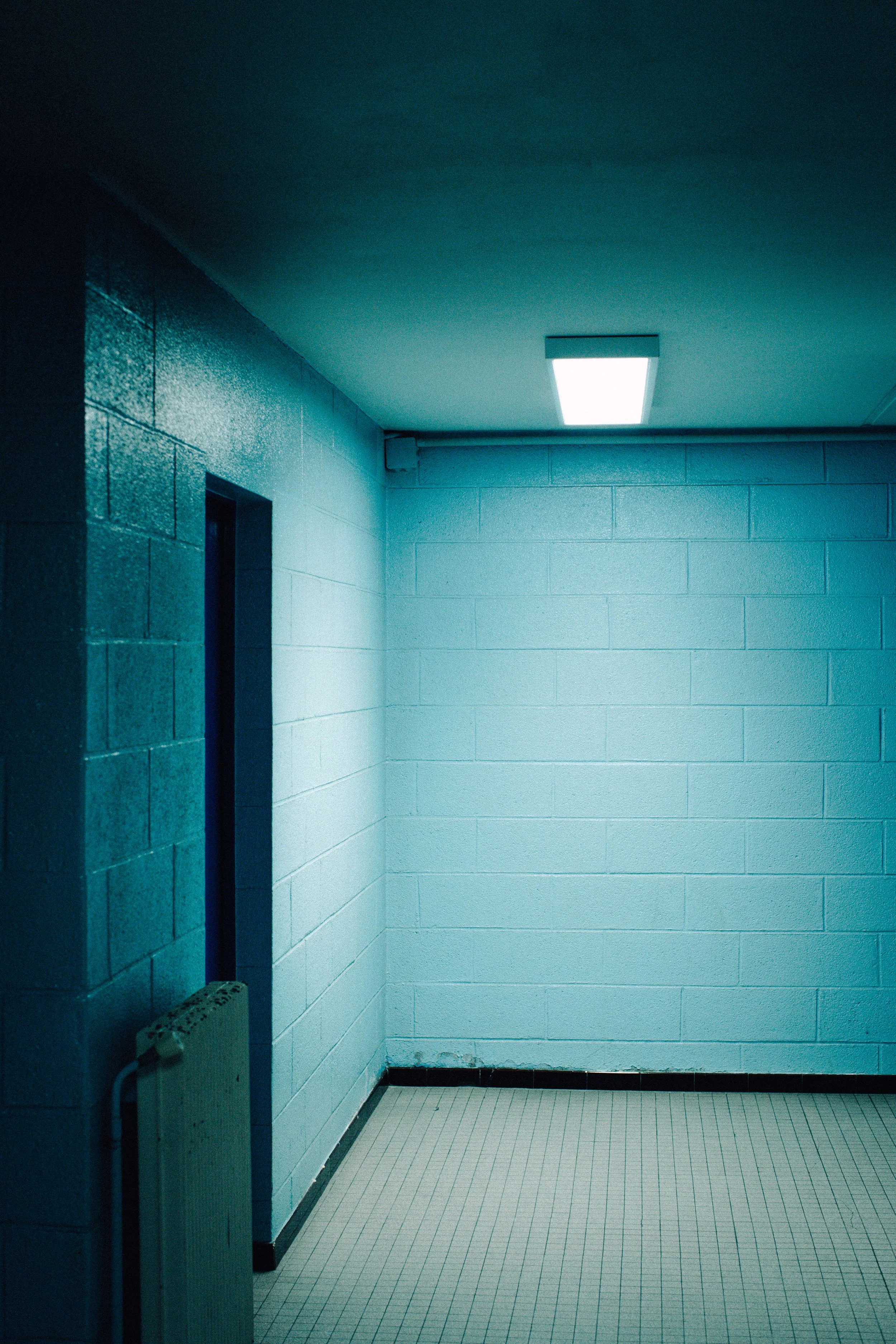 Empty, dimly lit interior space with tiled floor and painted cinder block walls, with a ceiling light fixture.