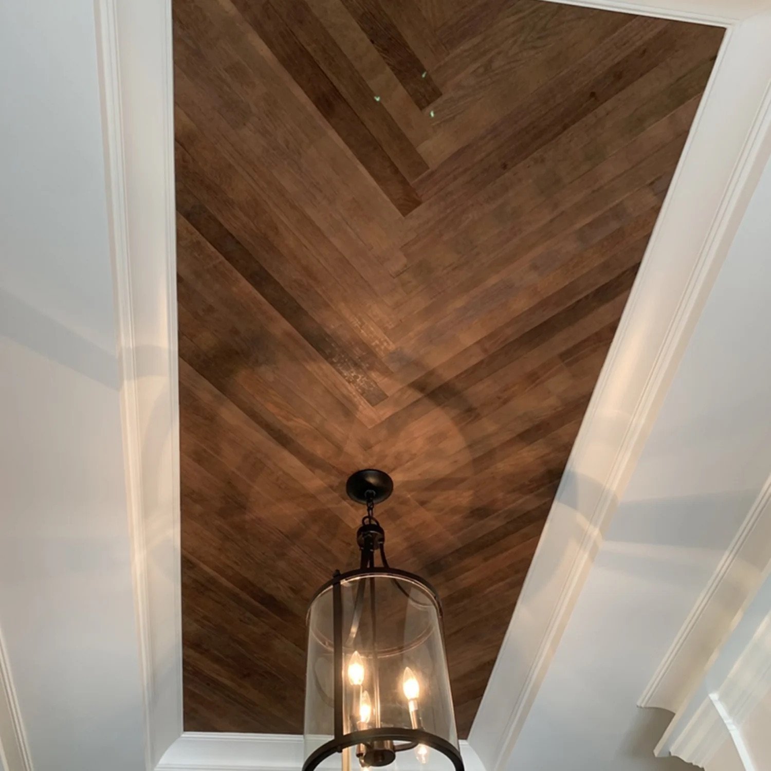 Ceiling with wooden panel design and a hanging light fixture with three bulbs.