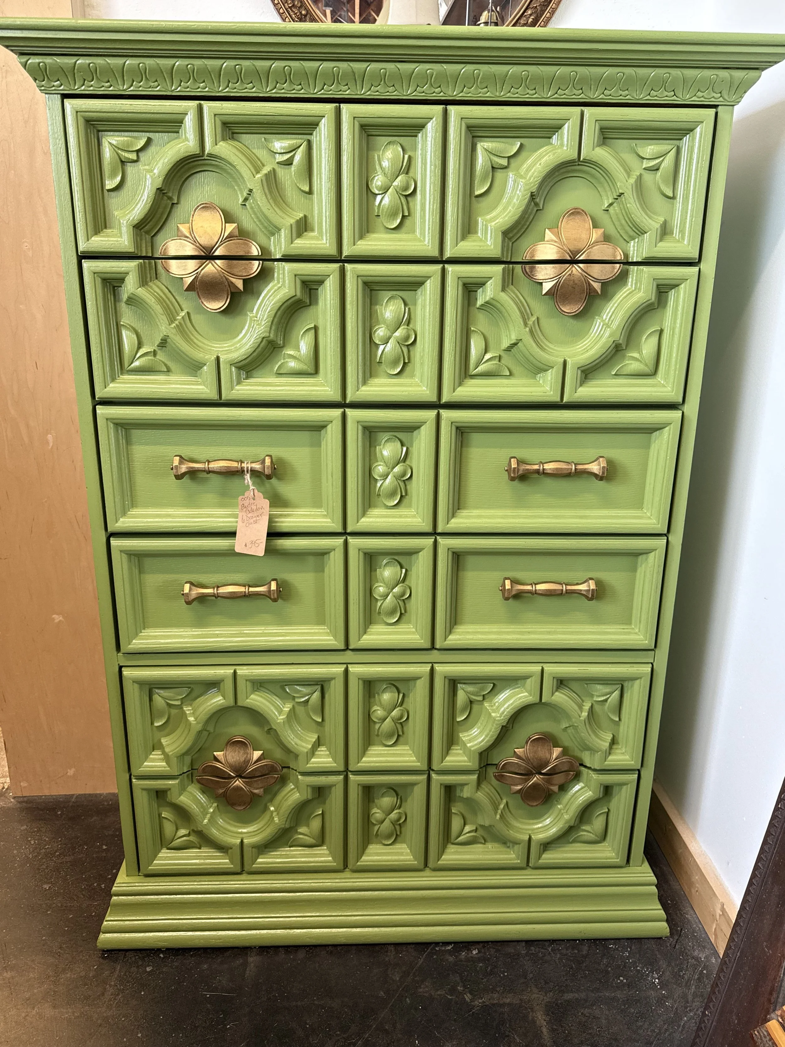Bright green decorative chest of drawers with gold floral hardware and carved floral and geometric details.