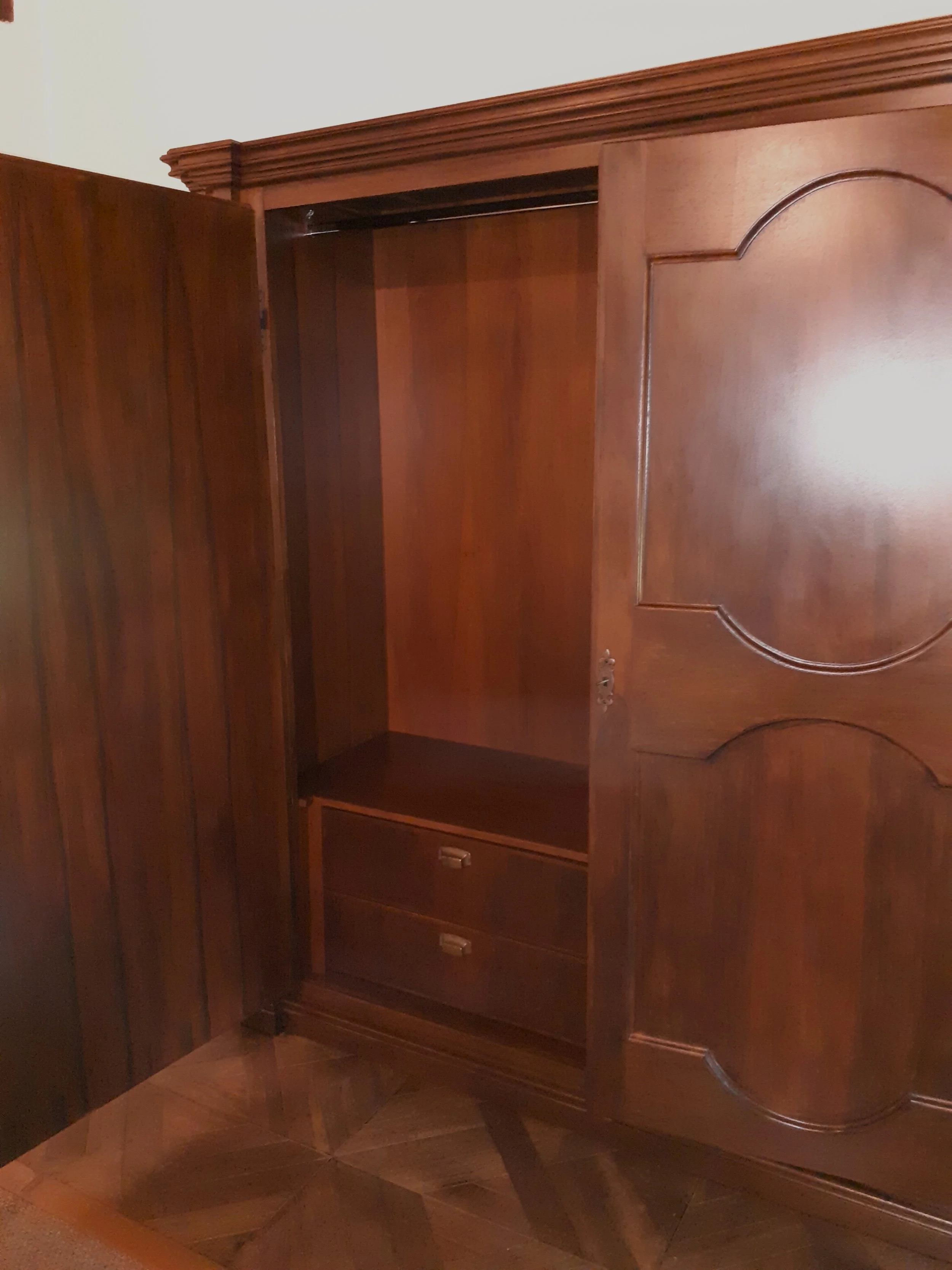 Armadio in legno con due ante aperte, due cassetti e una mensola interna.