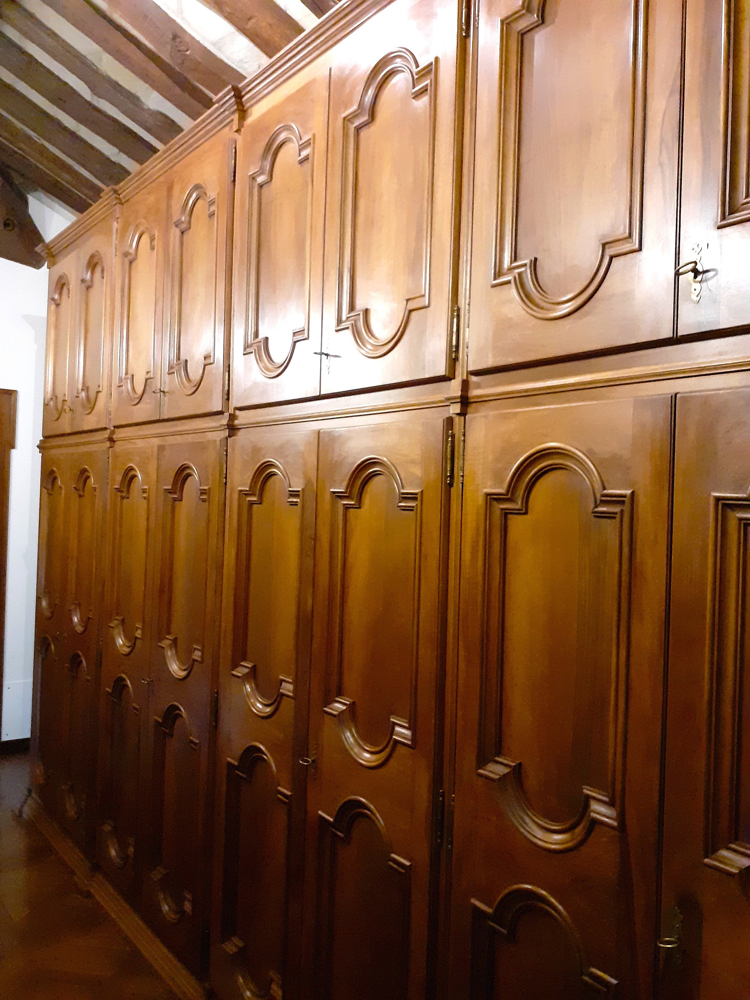 Armadi in legno con pannelli intagliati in un ambiente con soffitto con travi di legno.