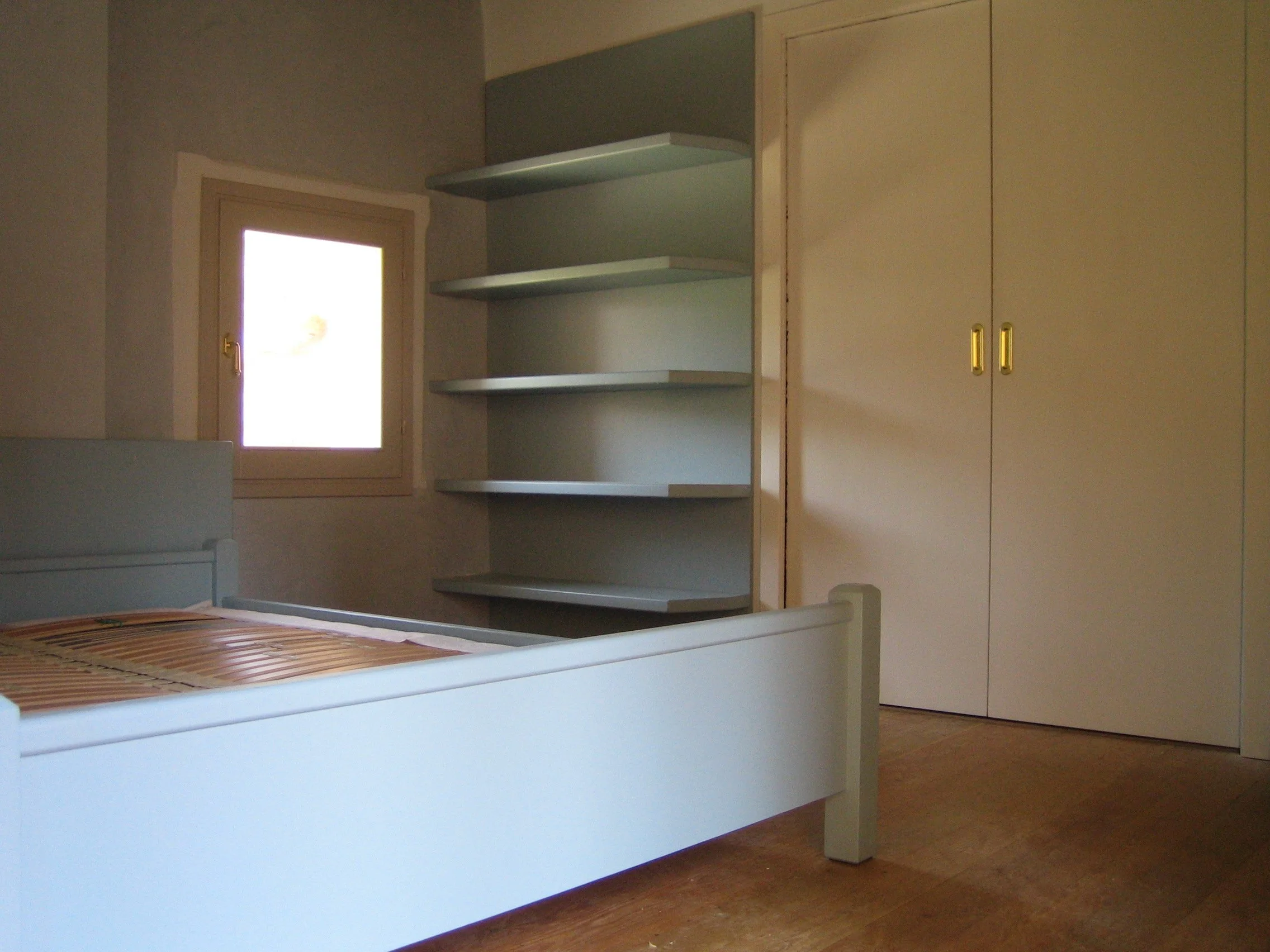 Camera con letto, finestra, armadio e mensole
