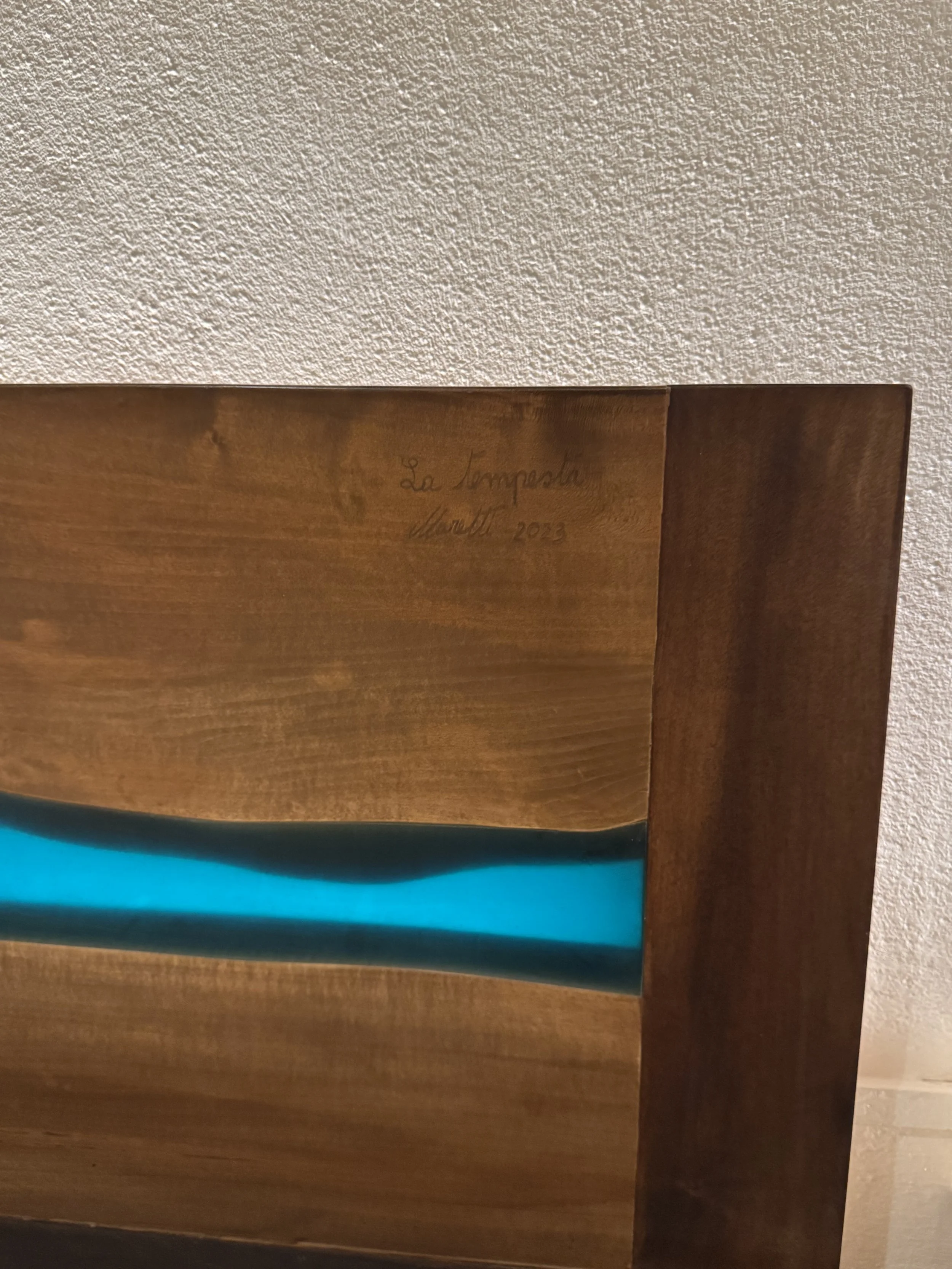 Dettaglio di una firma e data su un pezzo di legno di un mobile, scritto a mano con una penna, con testo che include 'La Tempesta', 'Maretti', e '2023'.