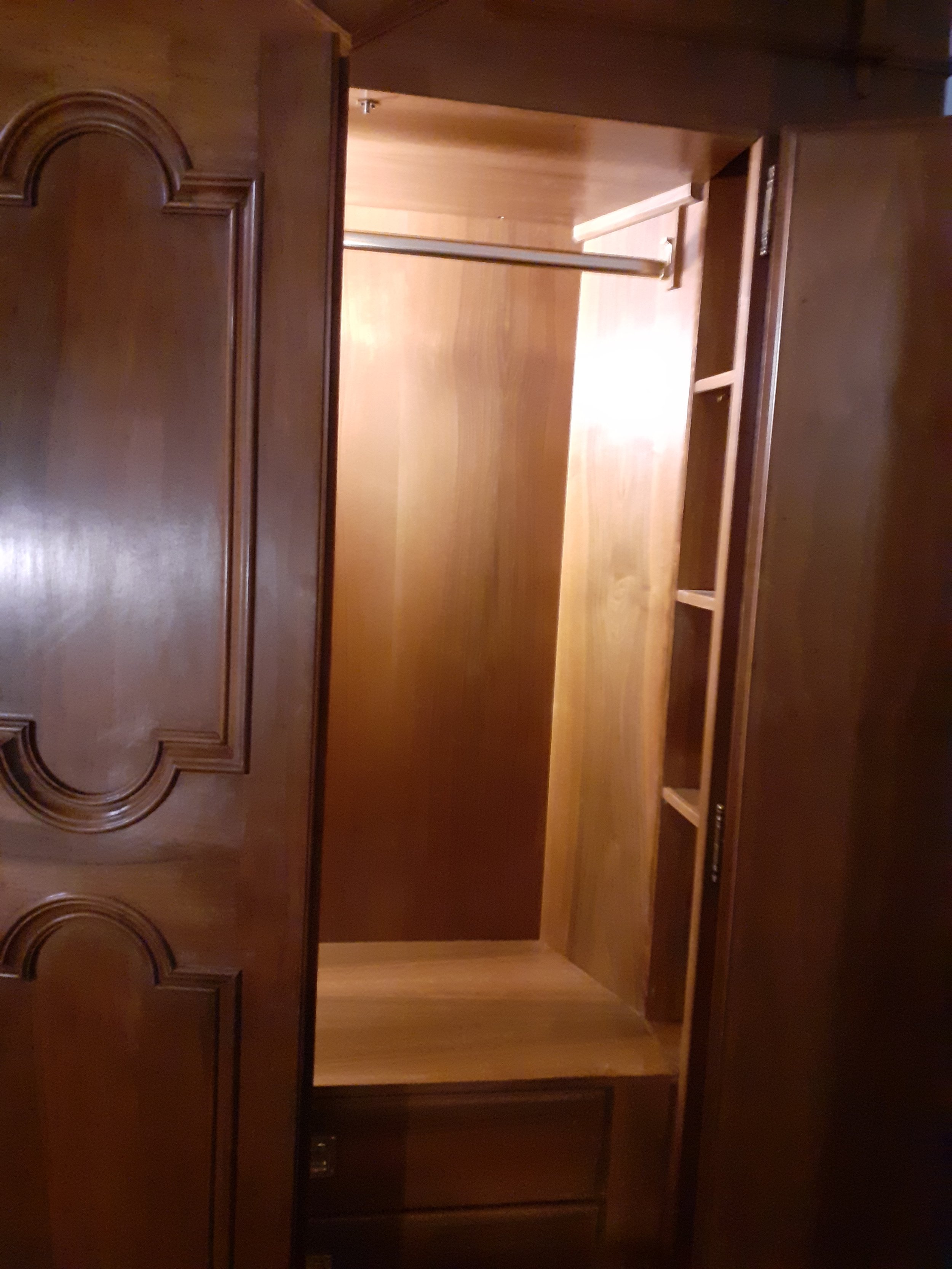 Armadio in legno aperto con ripiani e barra appendiabiti.