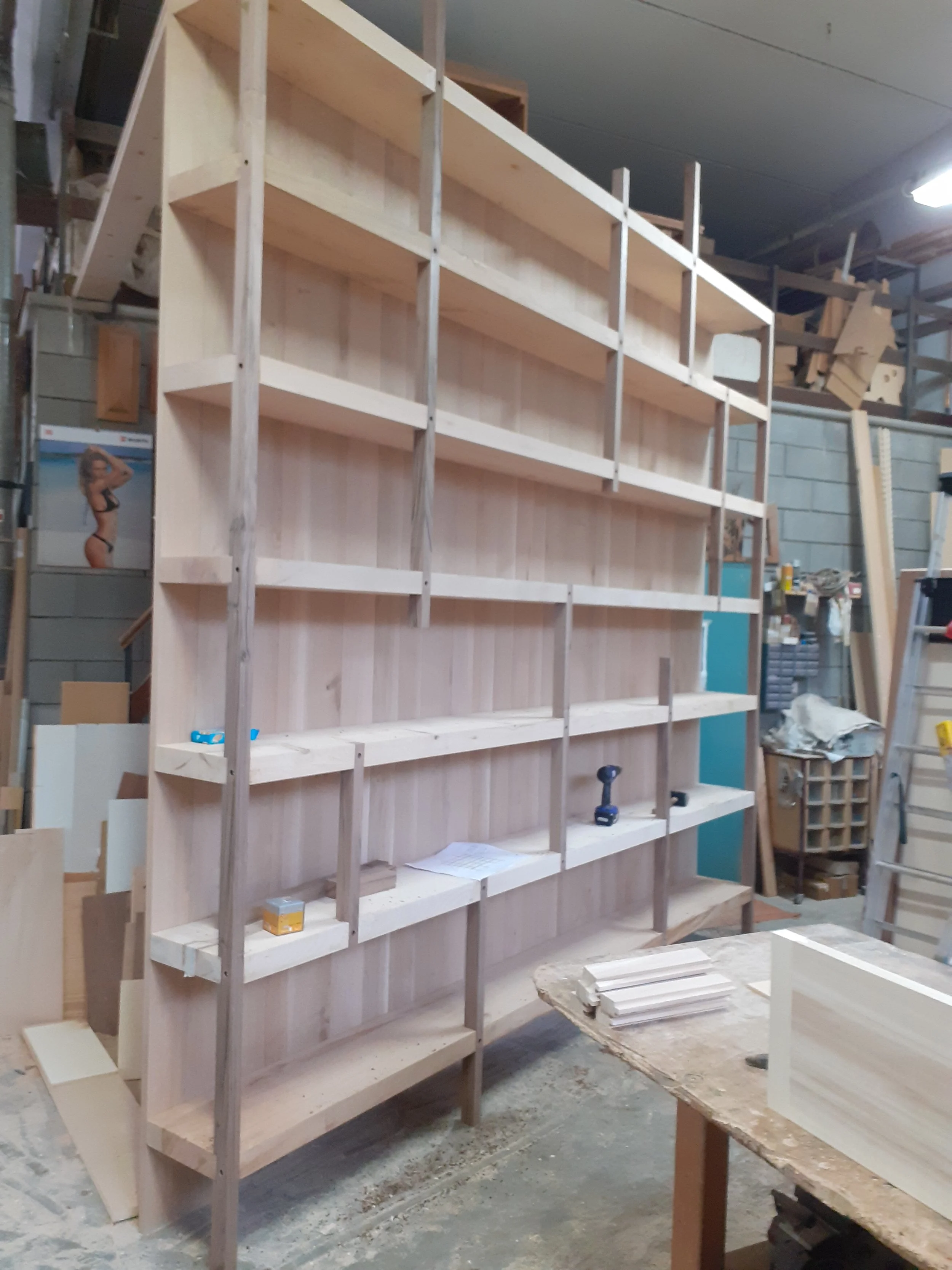 Mensola in legno in fase di costruzione, in un'officina con attrezzi e materiali da falegnameria.