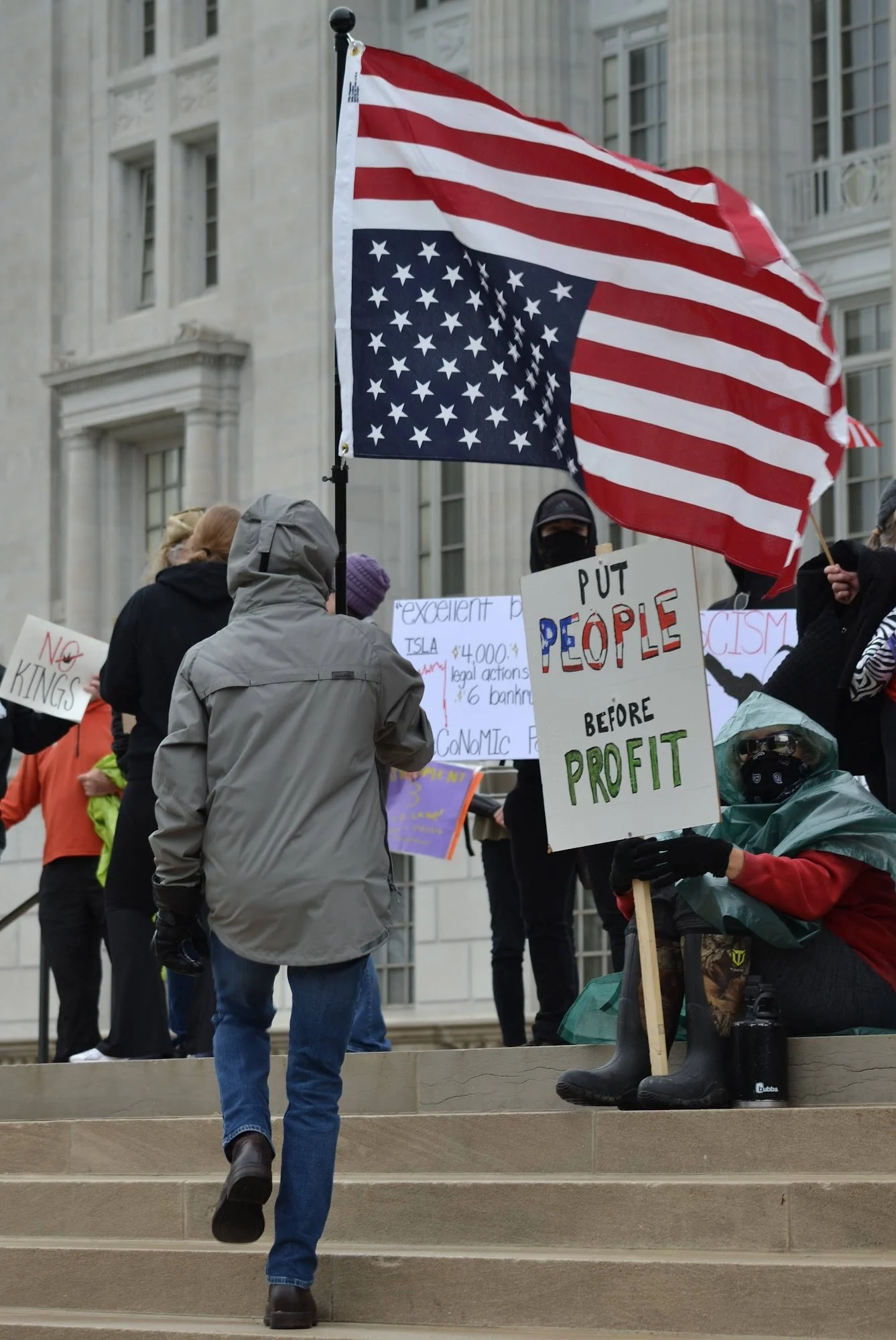 Protesters holding signs and an upside-down American flag during a demonstration.