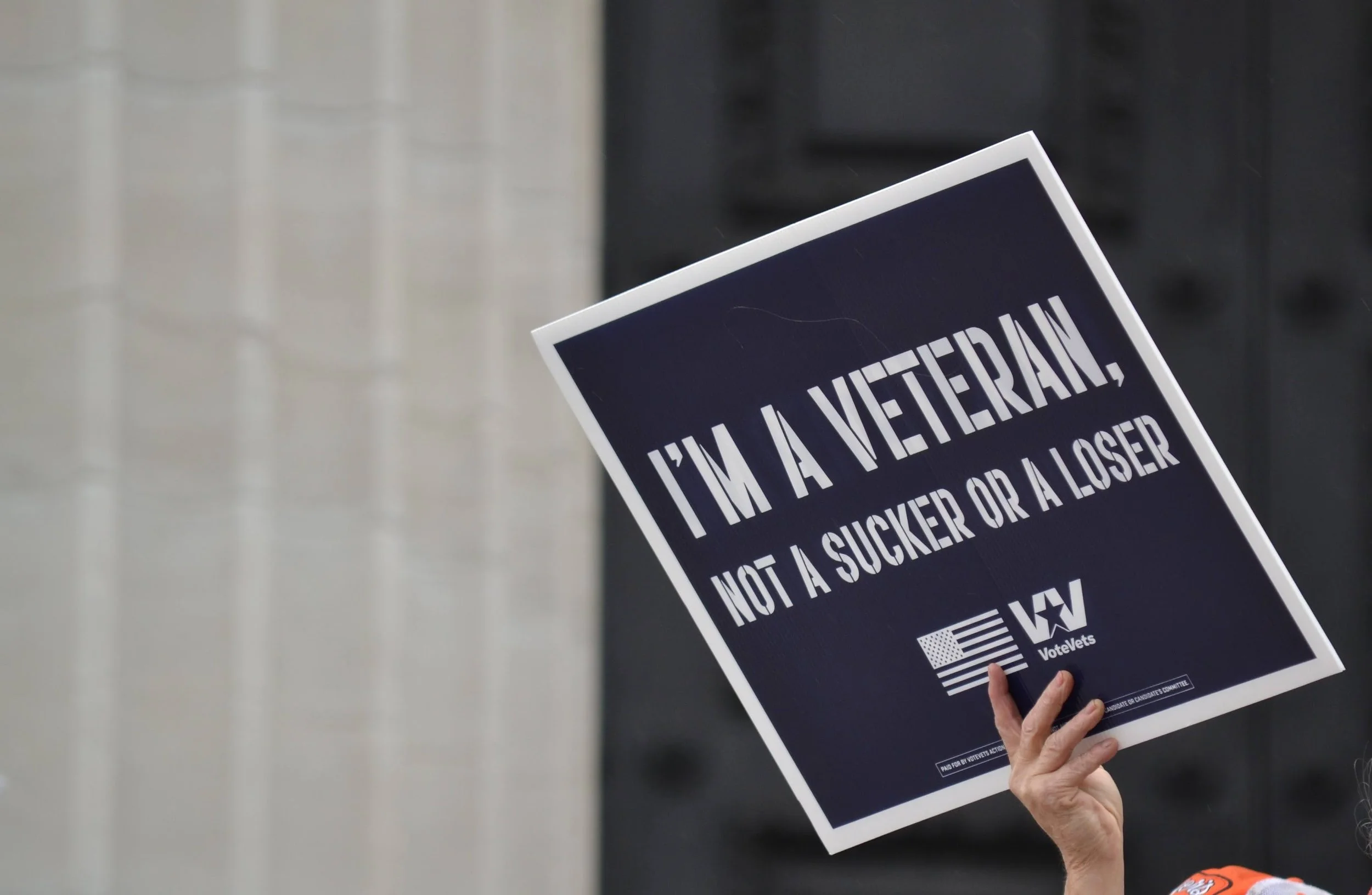 Sign reading 'I'm a veteran, not a sucker or a loser,' with a hand holding it.
