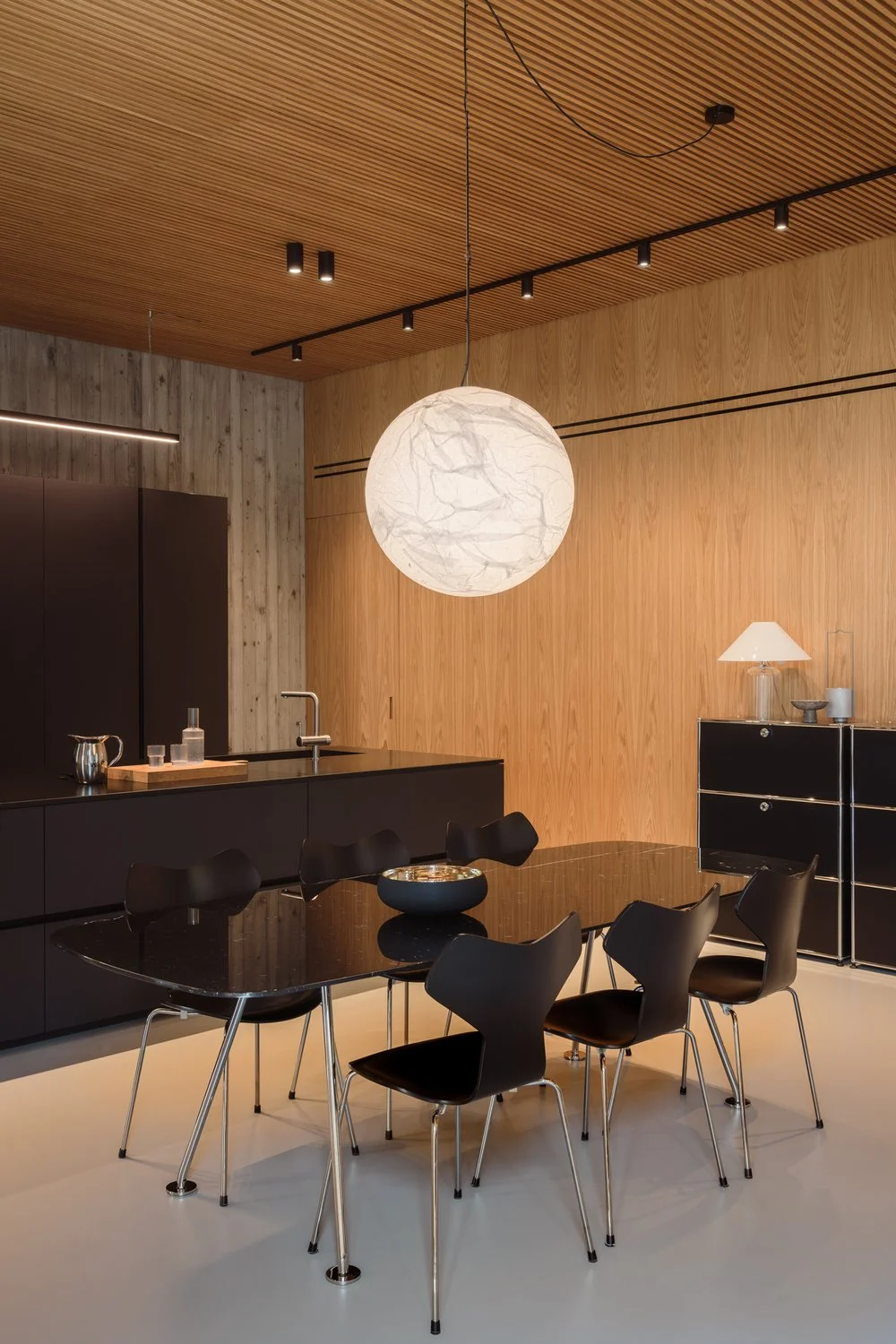 Modern black kitchen with 103 model chairs from Arne Jacobsen