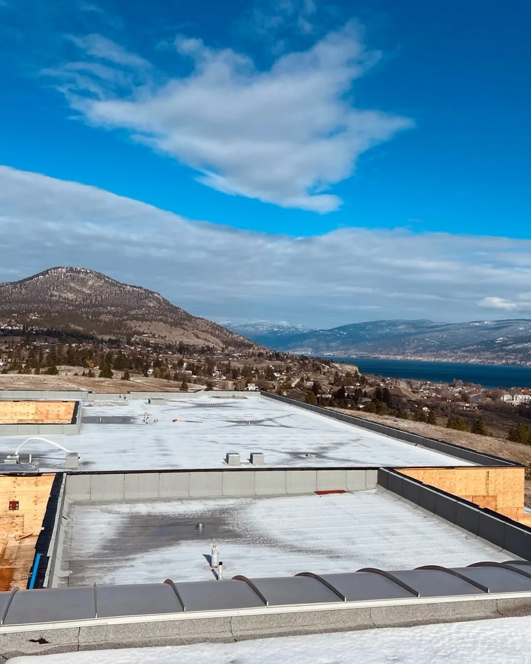 Progress looks pretty good from up here! 🌤️ Fresh roof installed on the PIB addition at Outma Sqilx&rsquo;w School while the Okanagan Valley puts on a show in the background. 
#BringingItAllTogether
