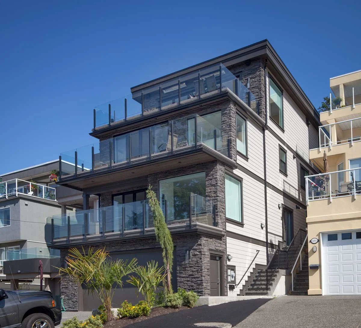 Modern multi-story house with glass railings and stone facade