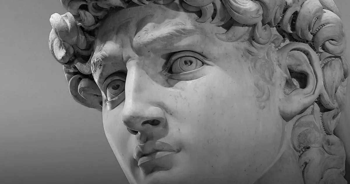 Close-up of a marble sculpture of a young person with curly hair, focusing on the face.