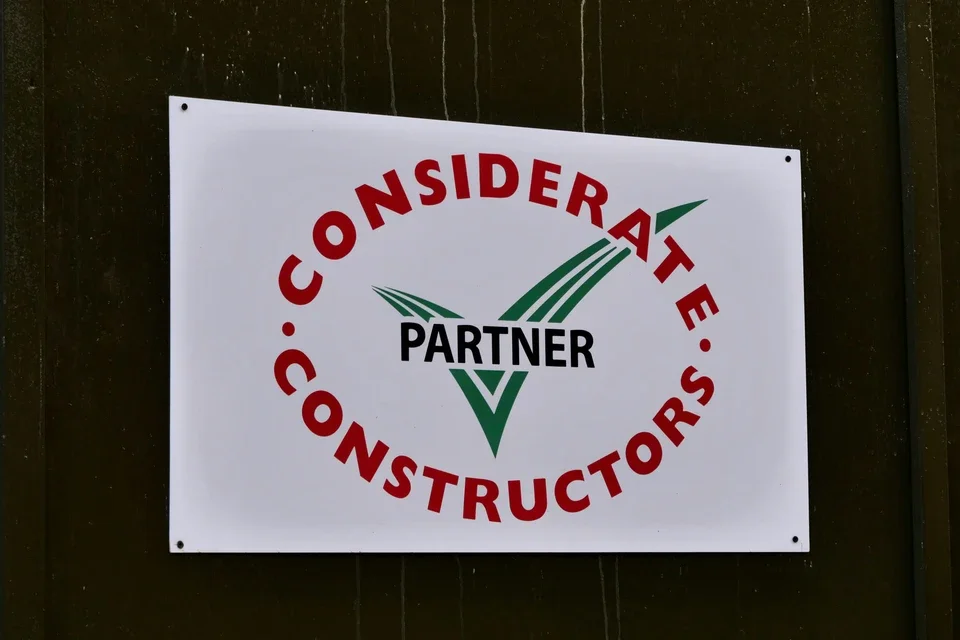 Panneau blanc avec un logo vert et noir, texte rouge indiquant 'CONSIDÉRAT E CONSTRUCTORS', et en son centre, le mot 'PARTNER' en noir.