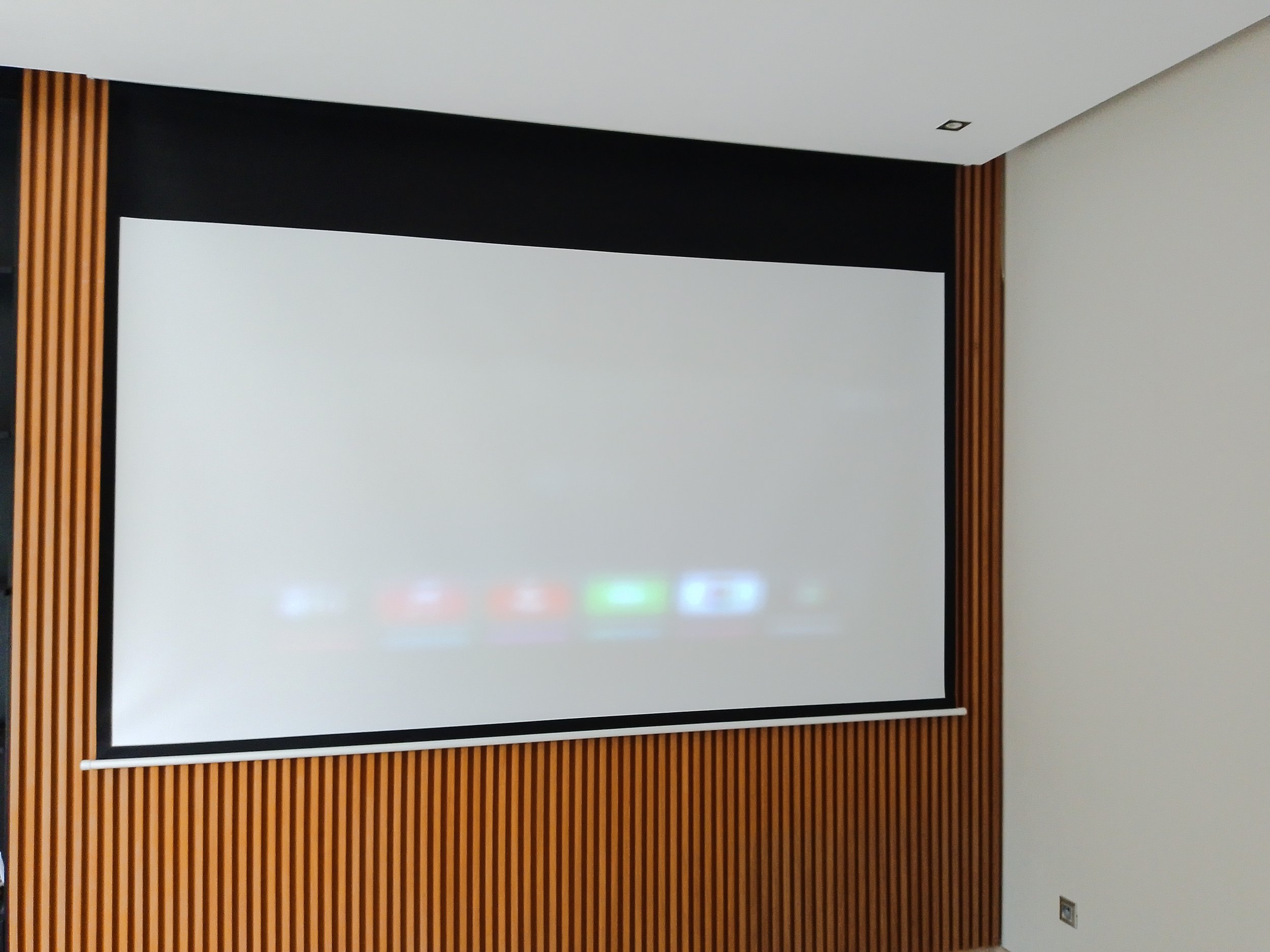 Écran de projection dans une salle avec murs en bois.