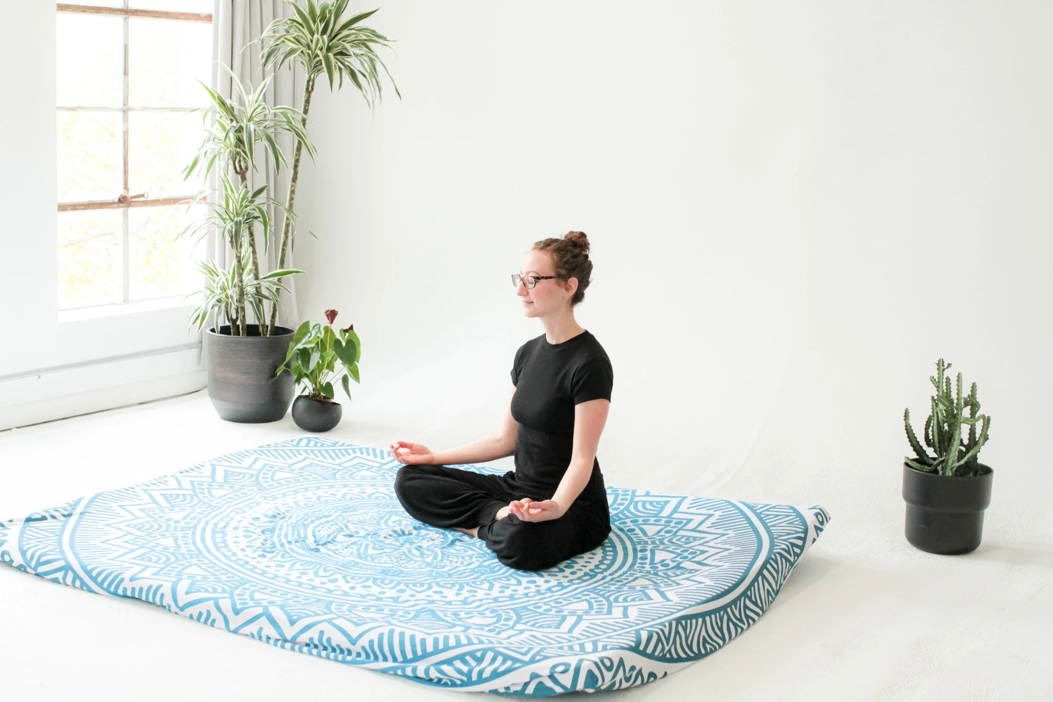 Paula sitting cross-legged in meditation on a yoga mat at Lovely Day Myofascial Release.
