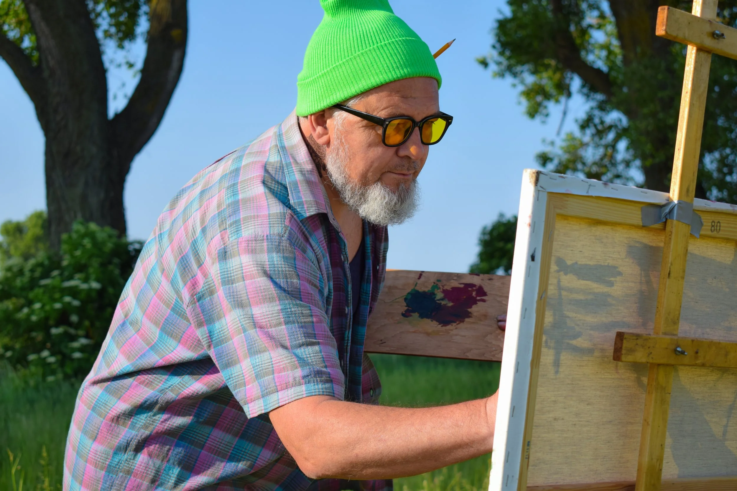 man wearing bright green hat and painting outside