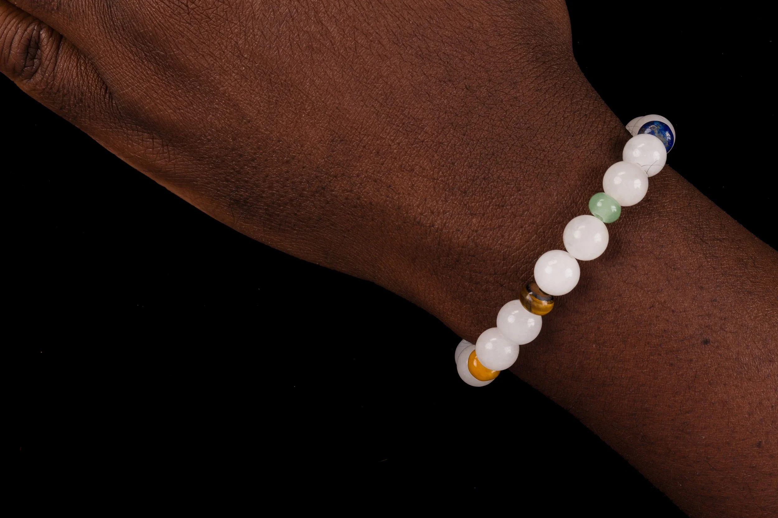 Enusia 7 chakra bracelet with white jade worn on wrist of African American arm