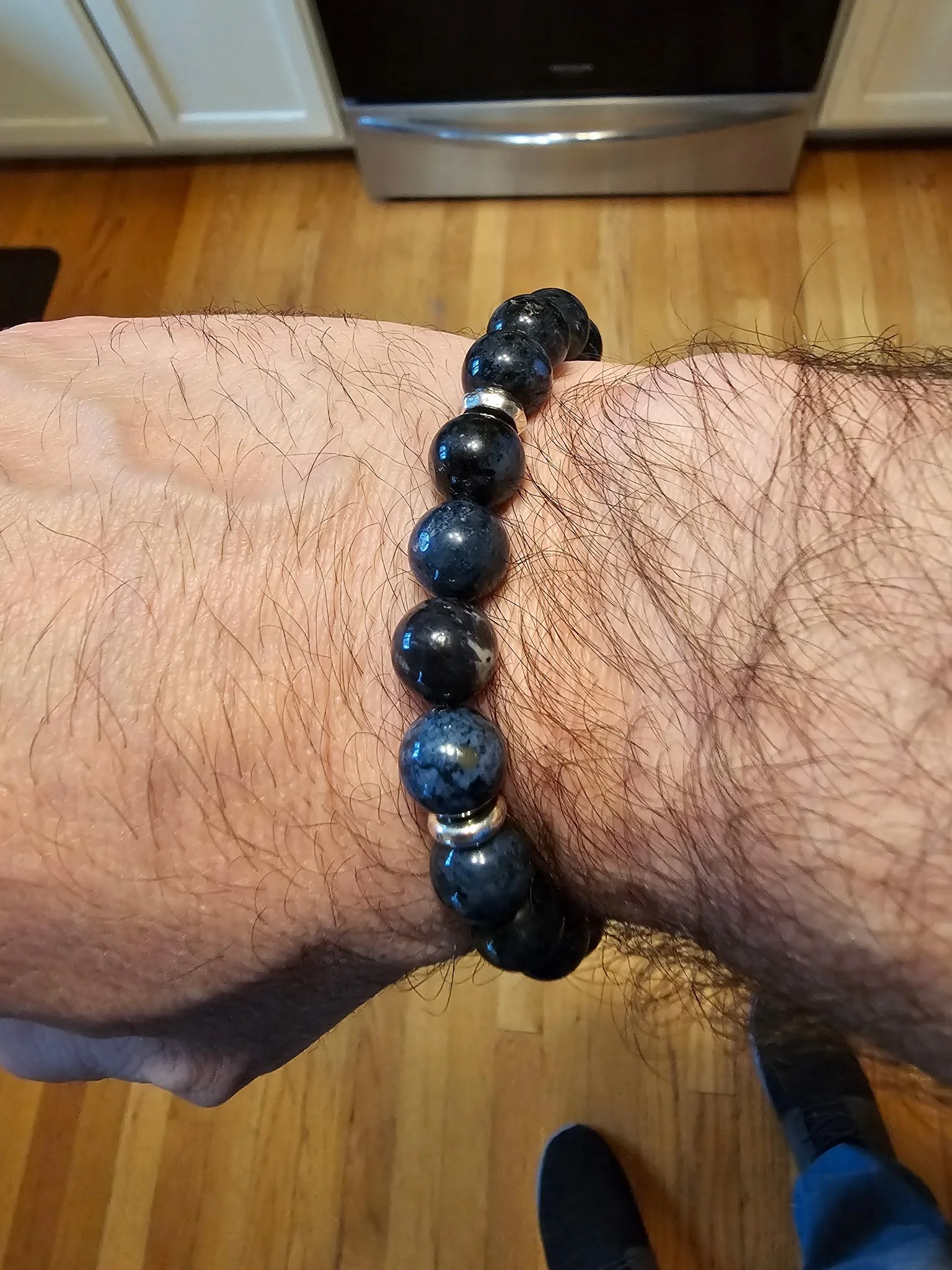 Man’s wrist wearing dark blue Enusia pill holder bracelet – Masculine beaded bracelet with hidden medicine storage, ideal for carrying pills such as nitroglycerin or anxiety medication.