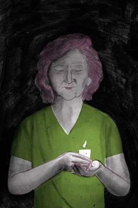 A woman with pink hair wearing a green shirt holding a lit candle in her hands.