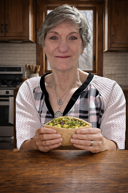 woman at table in kitchen eating a pita sandwich