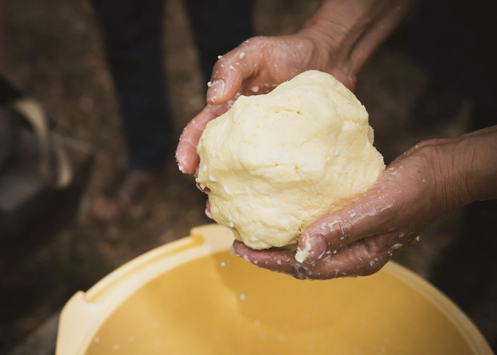 hands holding a fresh lump of butter over a bowl