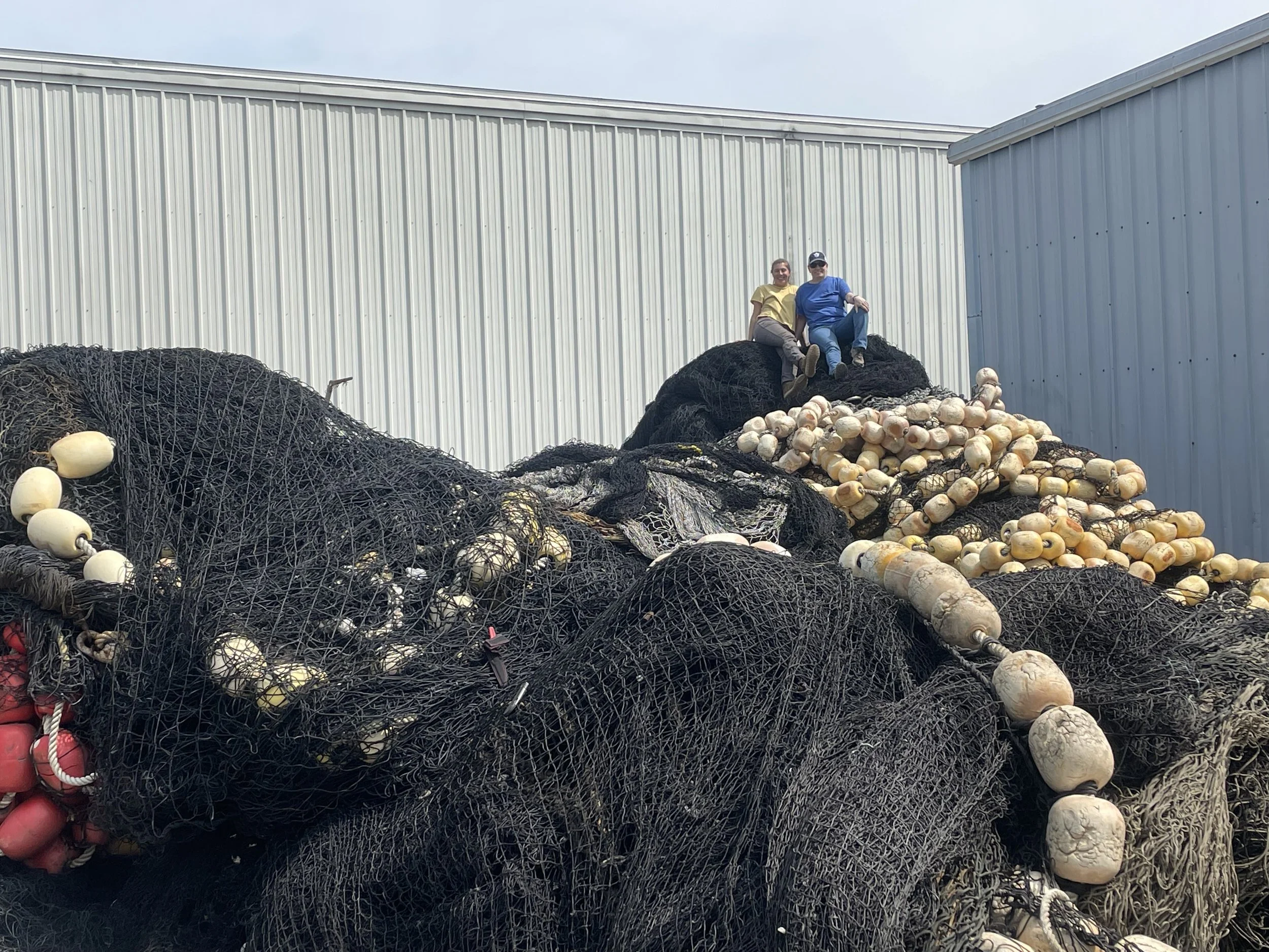 NYP staff member Caity with GOMLF staff Erin on a large end of life fishing net ready to be broken down.