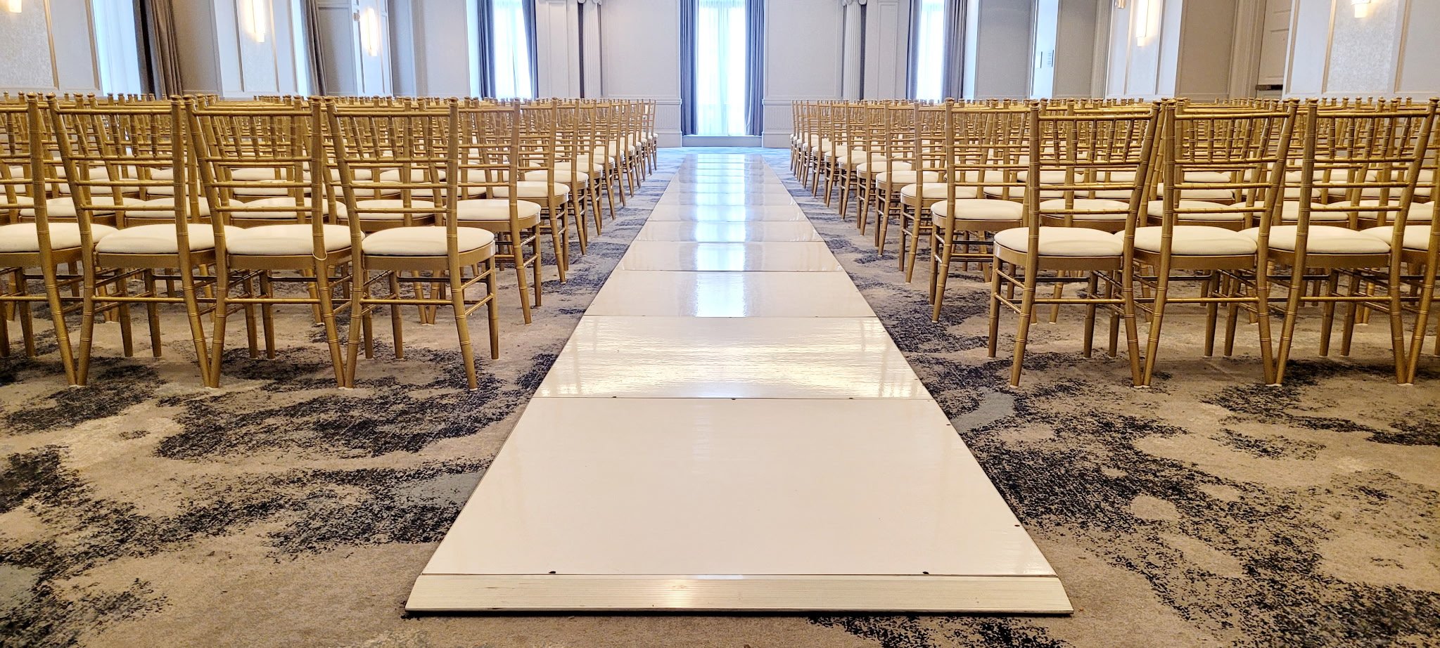 Dance floor style wedding aisle rental with gold Chiavari chairs for a defined indoor ceremony aisle.