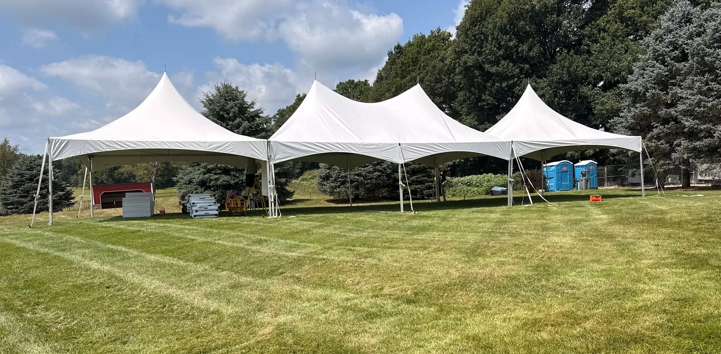 20x70 wedding tent package set up for 130 guests with tables and chairs for an outdoor wedding reception.