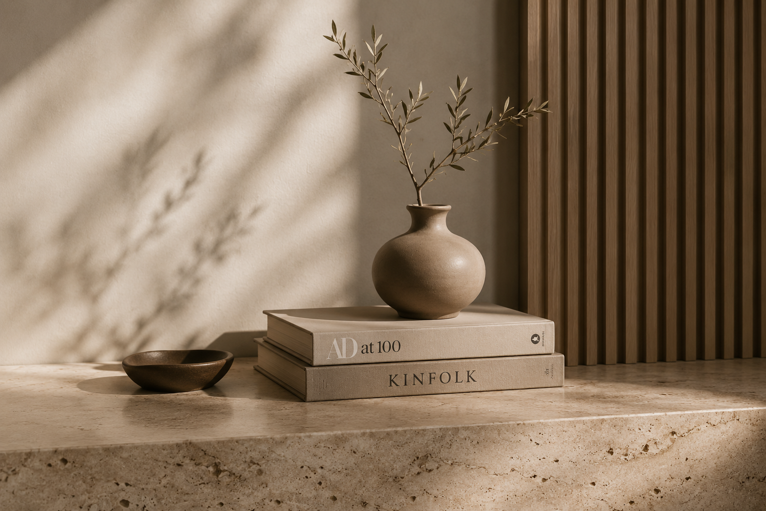 Ein minimalistisches Interior mit einer Steinkonsole, einem braunen Keramikvase mit Zweigen, einem kleinen braunen Schälchen, zwei Büchern und einer vertikalen Holzverkleidung in warmen Erdtönen.