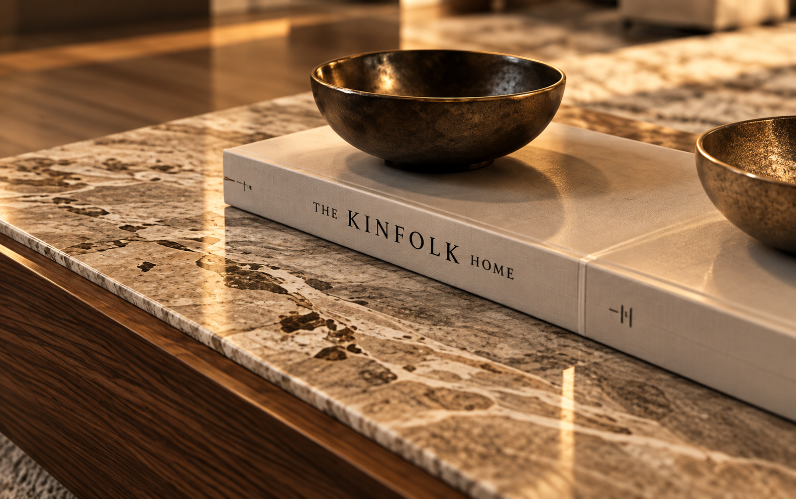 Detailvisualisierung einer Natursteinoberfläche mit dekorativer Metallschale und Interior-Design-Buch in warmem Tageslicht.
